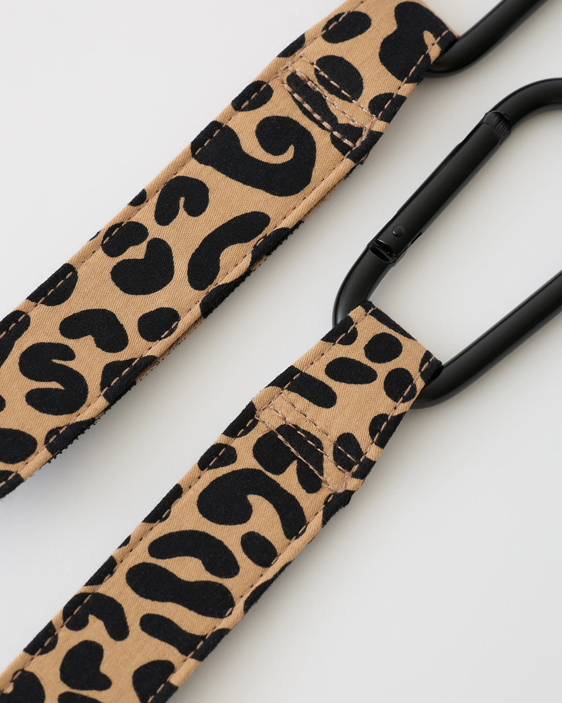 Close up of a pair of Stroller Party™ Clips (2-Pack) in Leopard on a beige background.