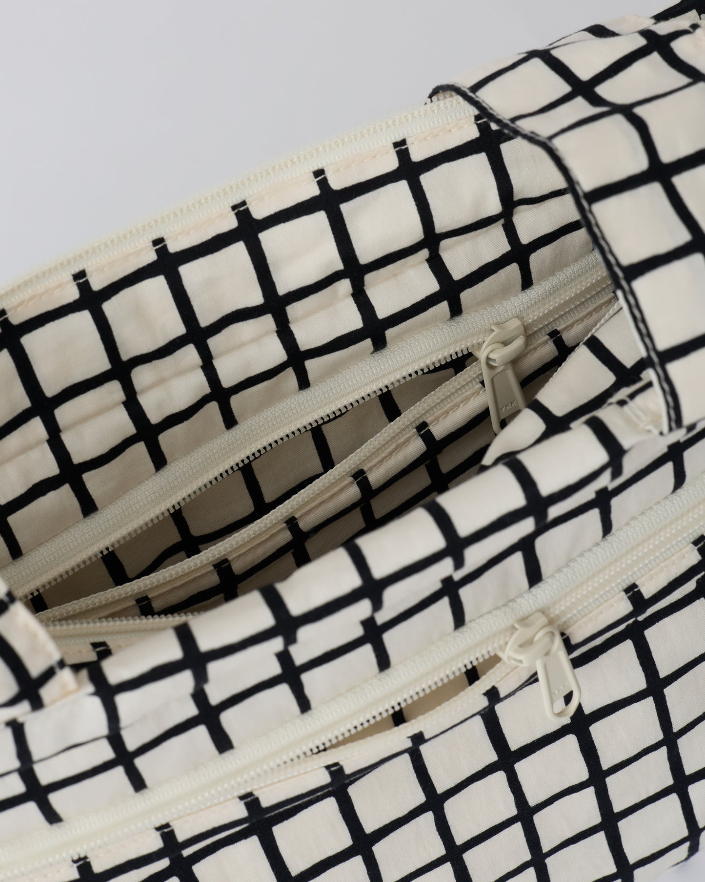 Close up of the interior pockets of the Stroller Party™ Caddy Bag in Black Grid, on a beige background.