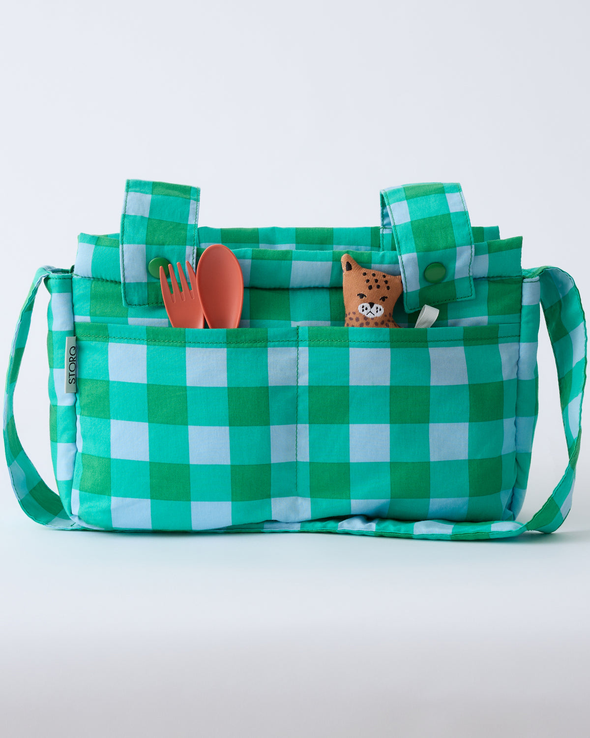 Stroller Party™ Caddy Bag in Teal Gingham, with spoon, fork and a little leopard lovey in the outer pockets, on a beige background.