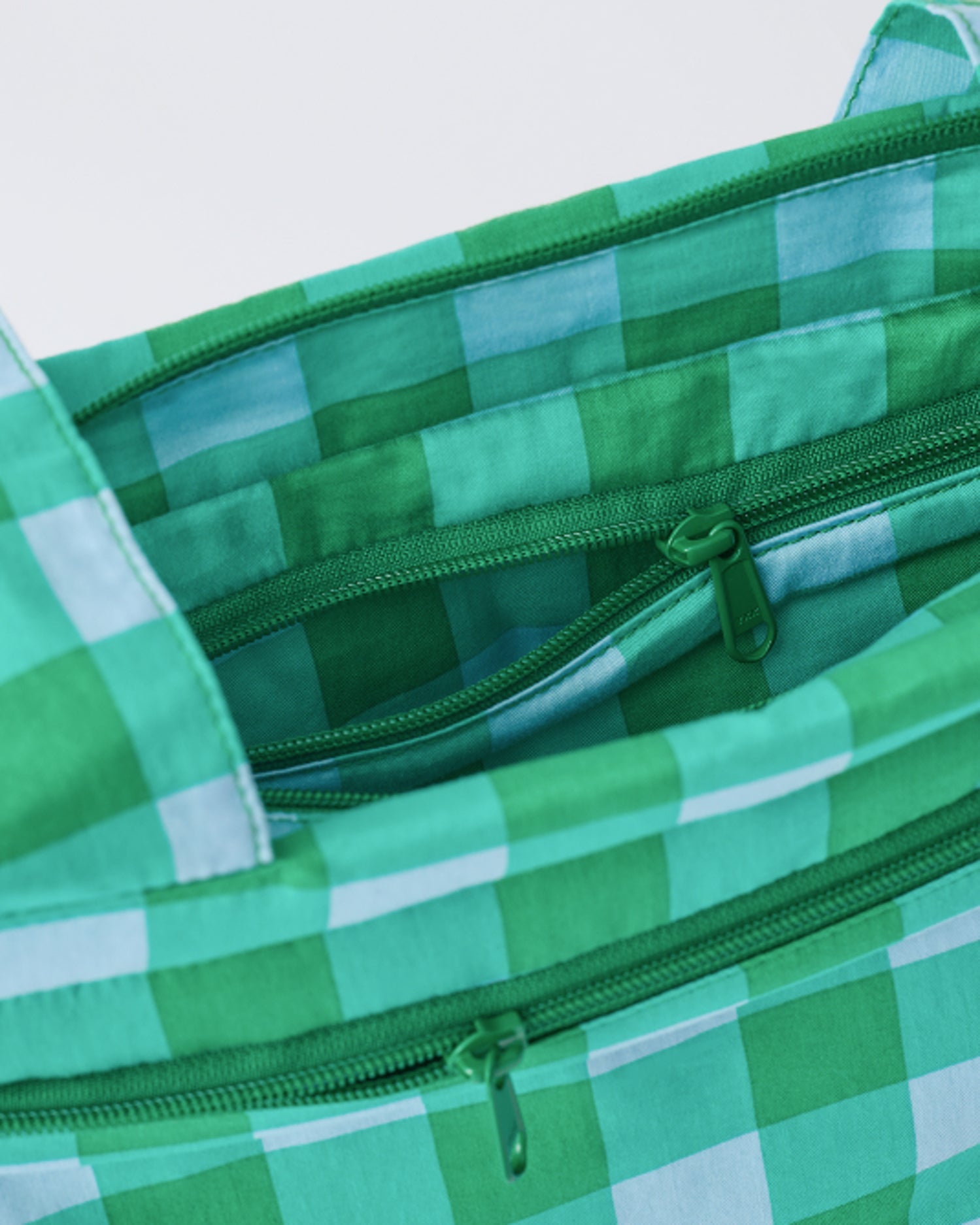 Close up of zippers of the Stroller Party™ Caddy Bag in Teal Gingham, on a beige background.