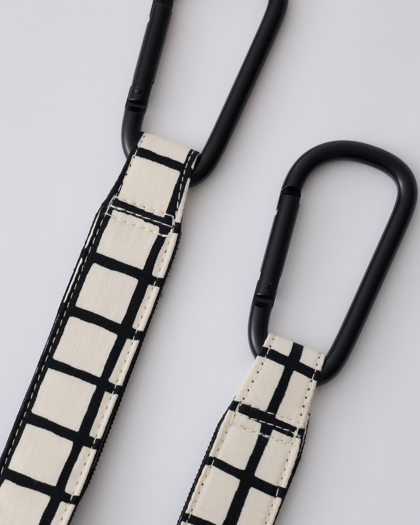 Stroller Party™ Clips (2-Pack) in Black Grid on a beige background.