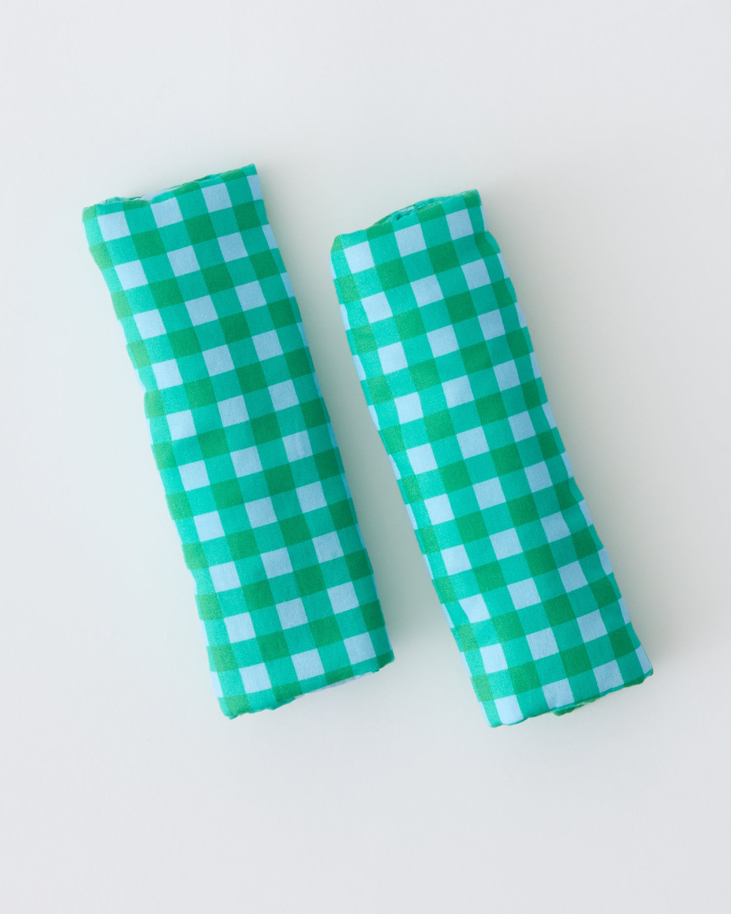 Folded Stroller Party™ Strap Covers in Teal Gingham on a beige background.