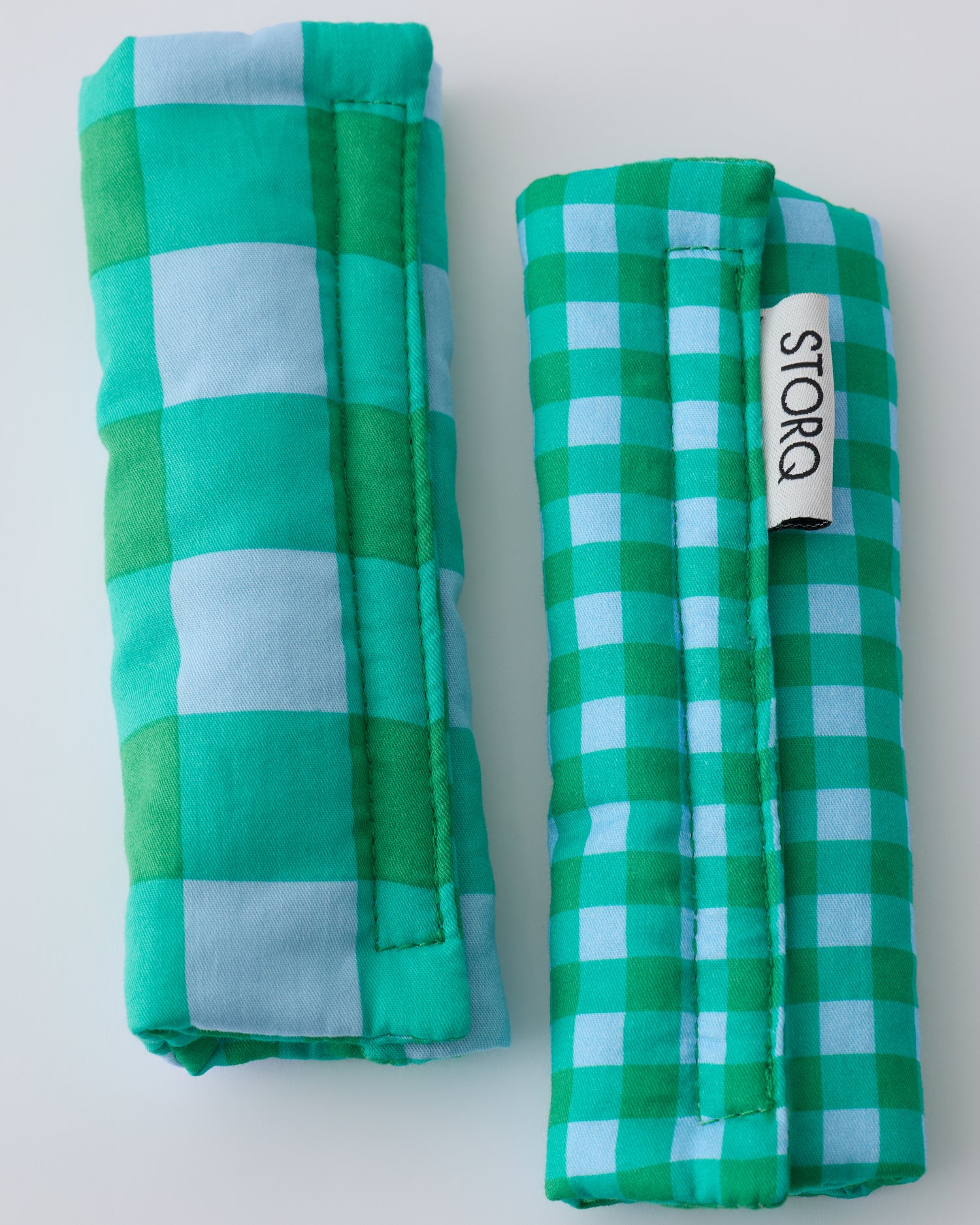 Folded Stroller Party™ Strap Covers in Teal Gingham on a beige background.