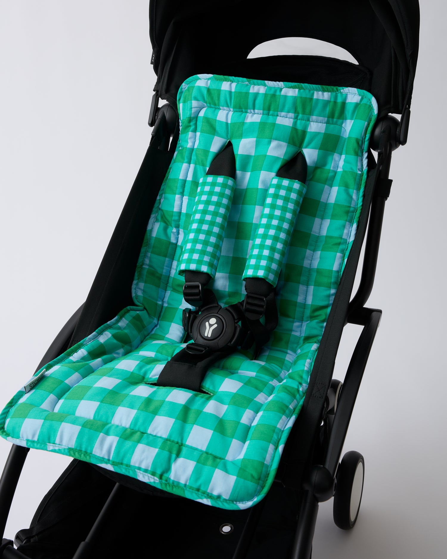 Black stroller with Stroller Party™ Seat Liner & Strap Covers in Teal Gingham on a beige background.
