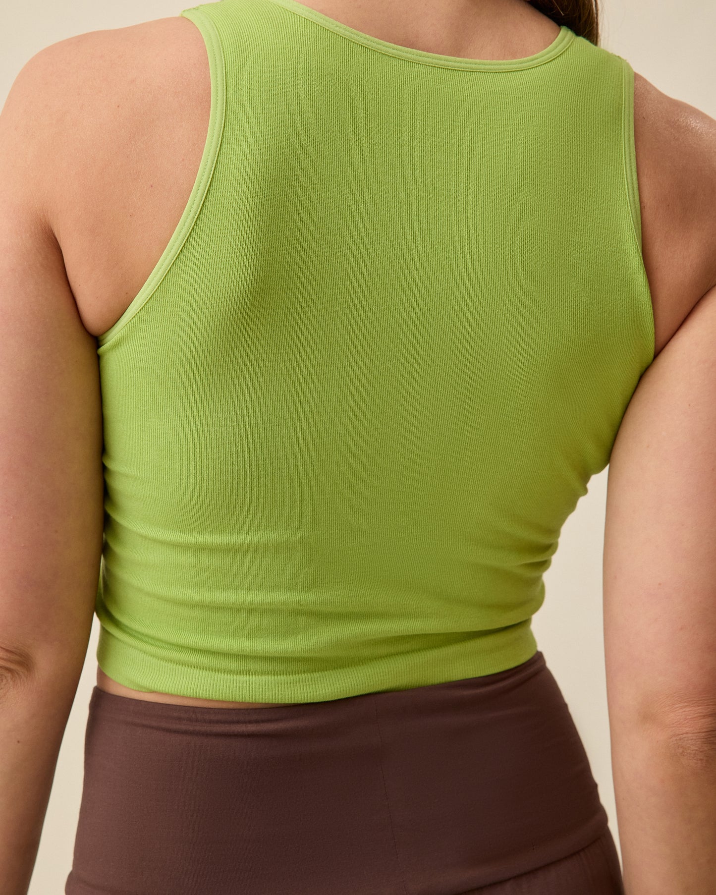 Model is displaying the back view on the Sublime® Bamboo Maternity & Nursing Longline Bra Top in Avocado on a beige background.