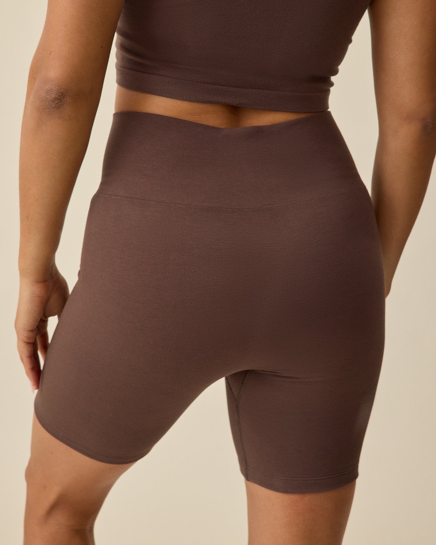 Back view of Model wearing Sublime® Bamboo Maternity & Postpartum Bike Short in Chocolate on a beige background 