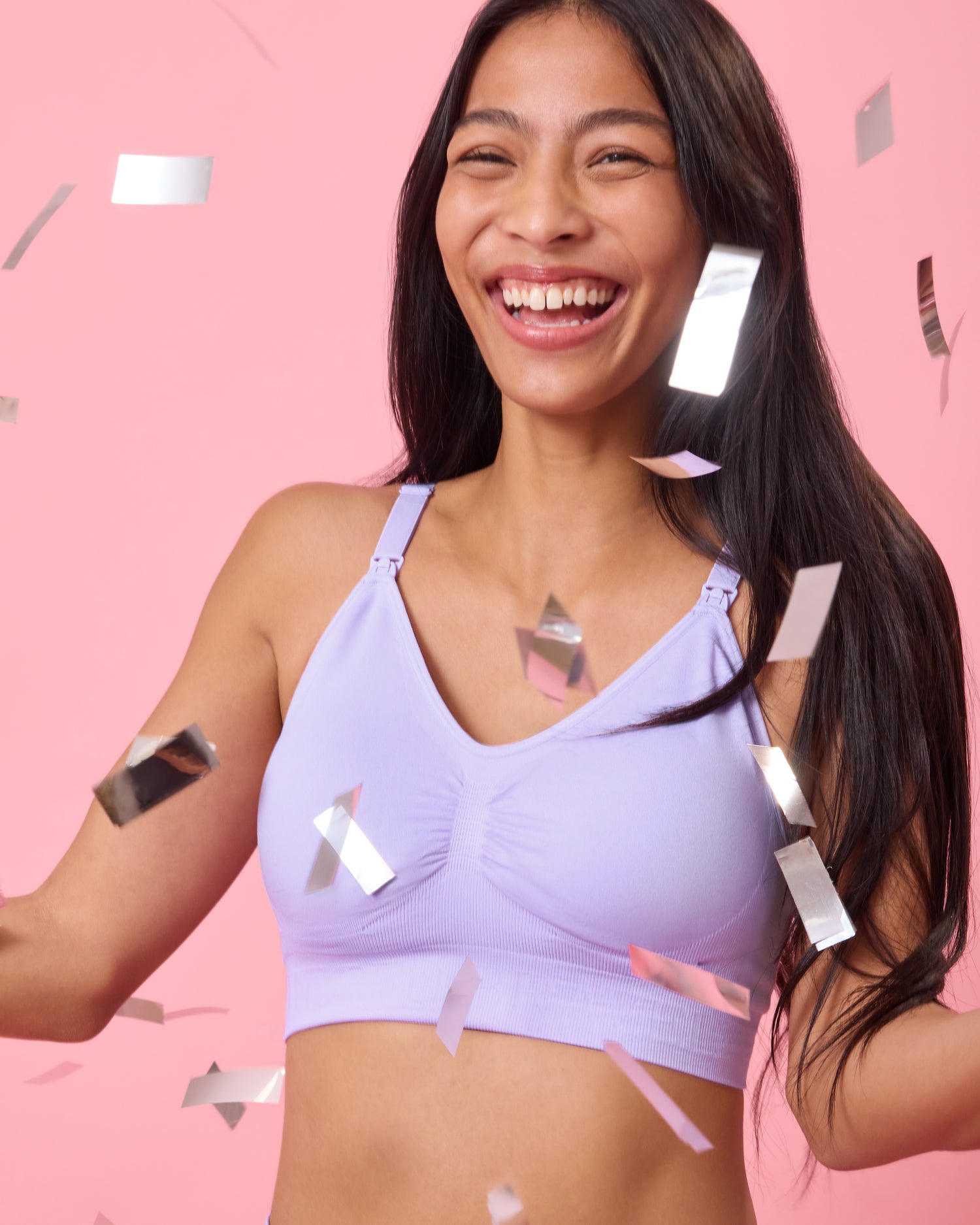Front view of model wearing Simply Sublime Nursing Bra in Lavender on a pink background laughing happily with confetti falling around her