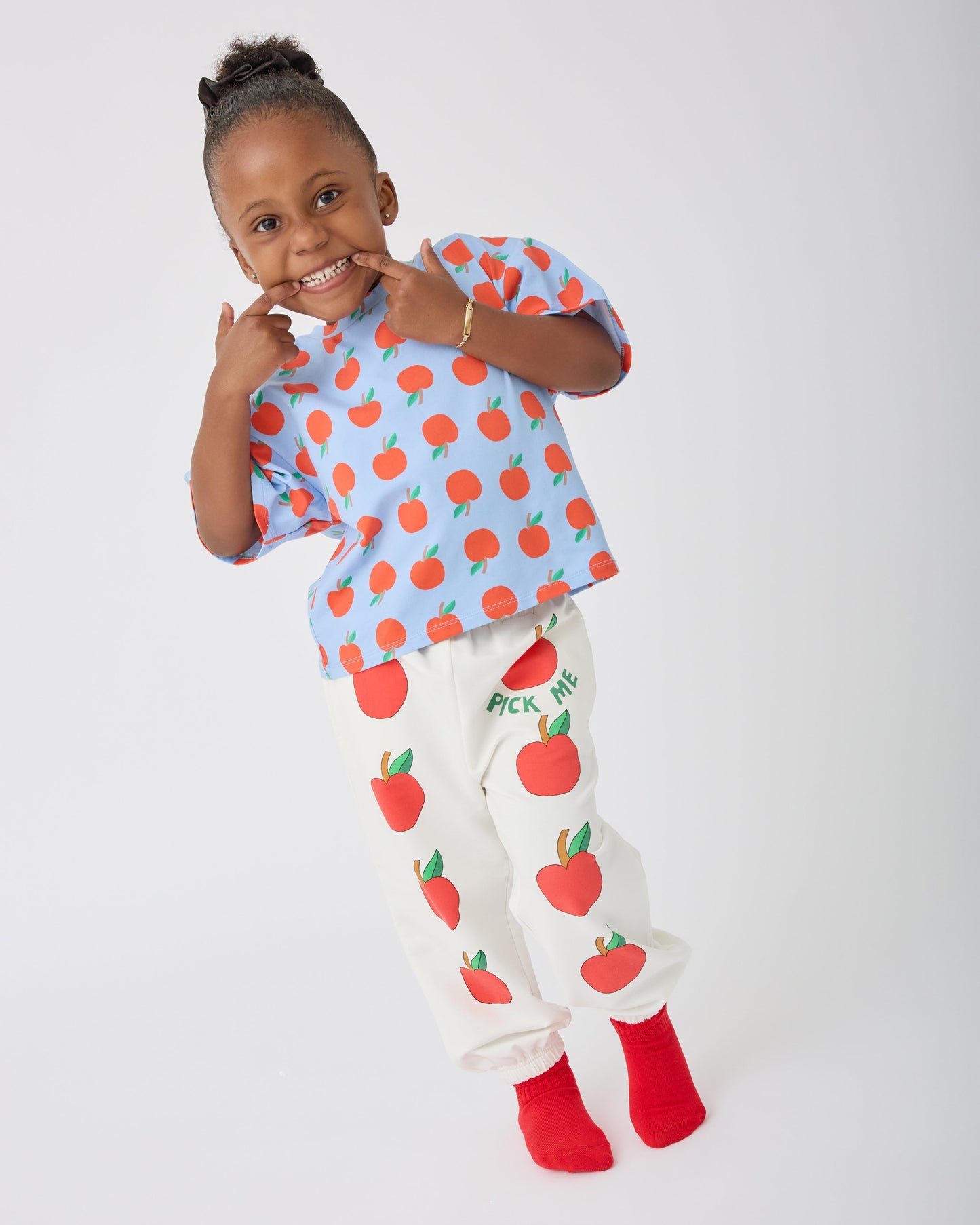 Model is wearing Graphic Tee in Blue Apple and French Terry Jogger in Ivory Apple on a gray background.@model_info:Aliyana is 4 years old and wearing 4T.