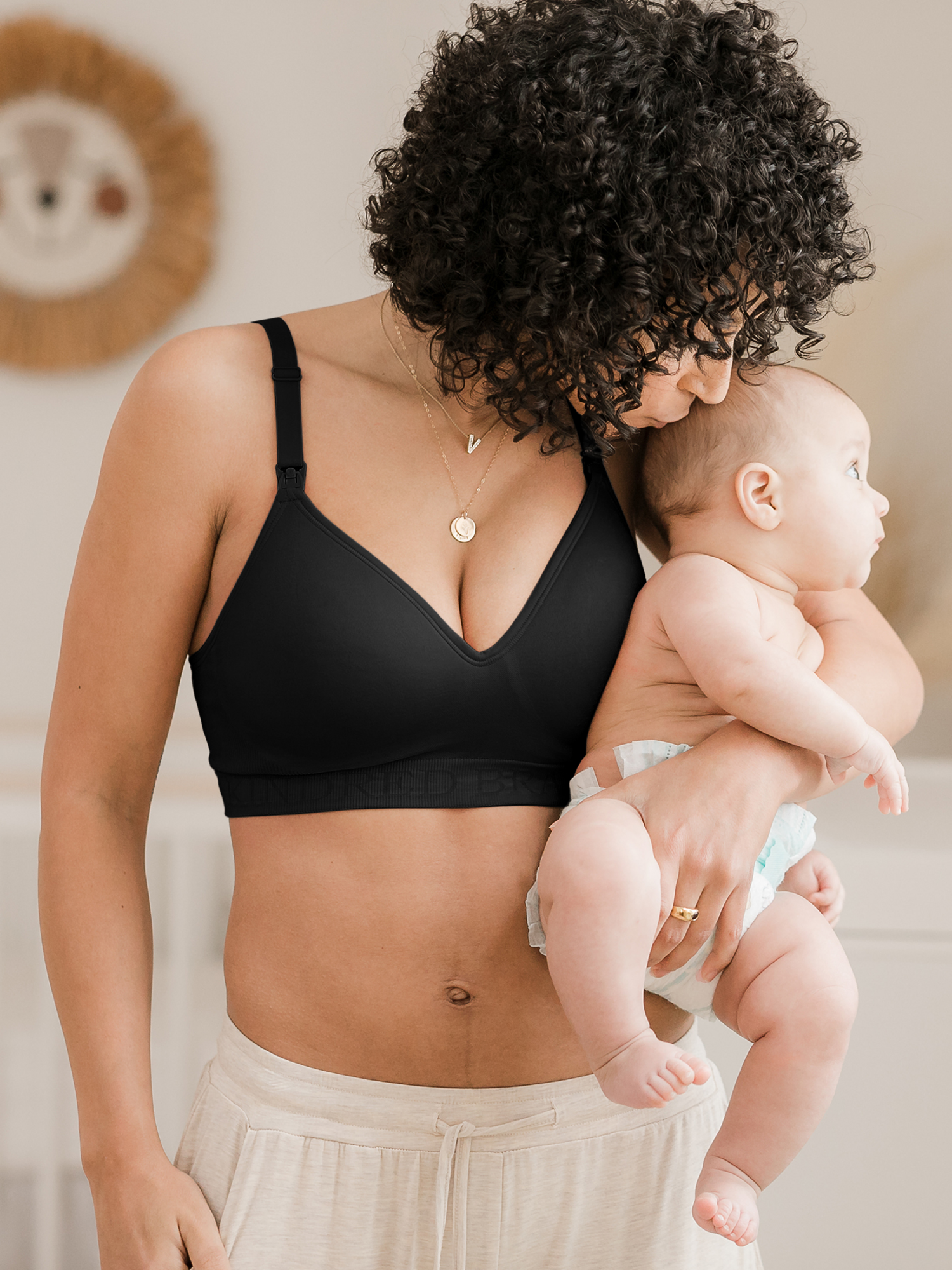 Model holding her baby on her hip while wearing the Signature Sublime® Contour Maternity & Nursing Bra in Black @model_info:Arion is wearing a Small.