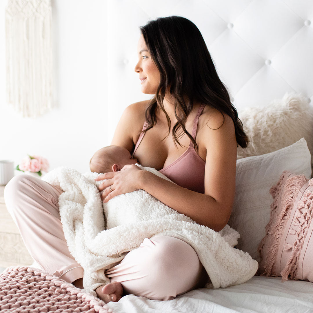 Model breastfeeding her baby while wearing the Simply Sublime® Lace Racerback Nursing Bra | Rose