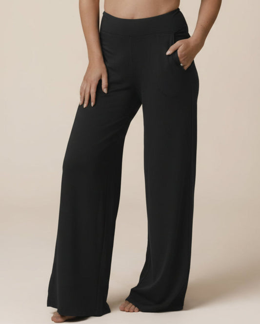 Black bamboo wide leg lounge pants worn by a person on a beige background