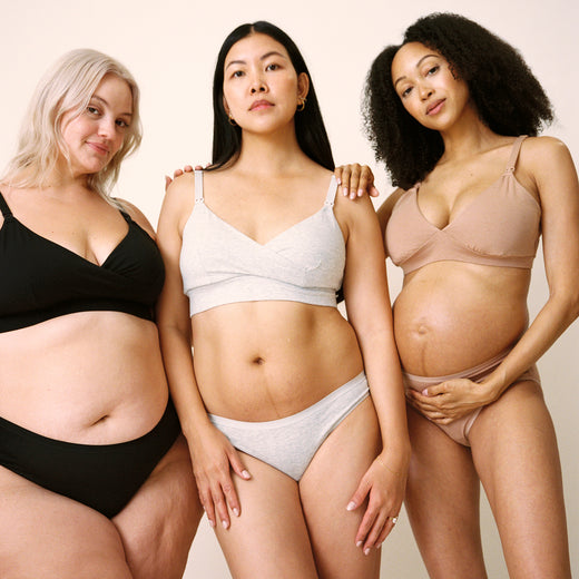 Postpartum model on the right is wearing SoftStretch Cotton Nursing Bra and SoftStretch Cotton Maternity & Postpartum Hipster in Grey Heather. Pregnant model in the middle is wearing SoftStretch Cotton Maternity & Nursing Bralette and SoftStretch Cotton Maternity & Postpartum Brief in Buff. Model on left is wearing SoftStretch Cotton Nursing Bra and SoftStretch Cotton Maternity & Postpartum Thong in Black on a beige background. 