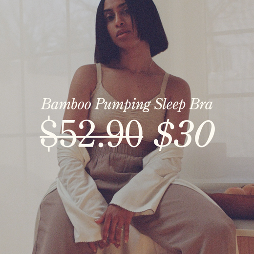 White type over image reads: Bamboo Pumping Sleep Bra. $52.90 with a strikethrough. $30. Image of woman lounging on kitchen counter next to bowl of fruit, while wearing nursing bra, bottoms and Cotton Bamboo Robe in Ivory. 