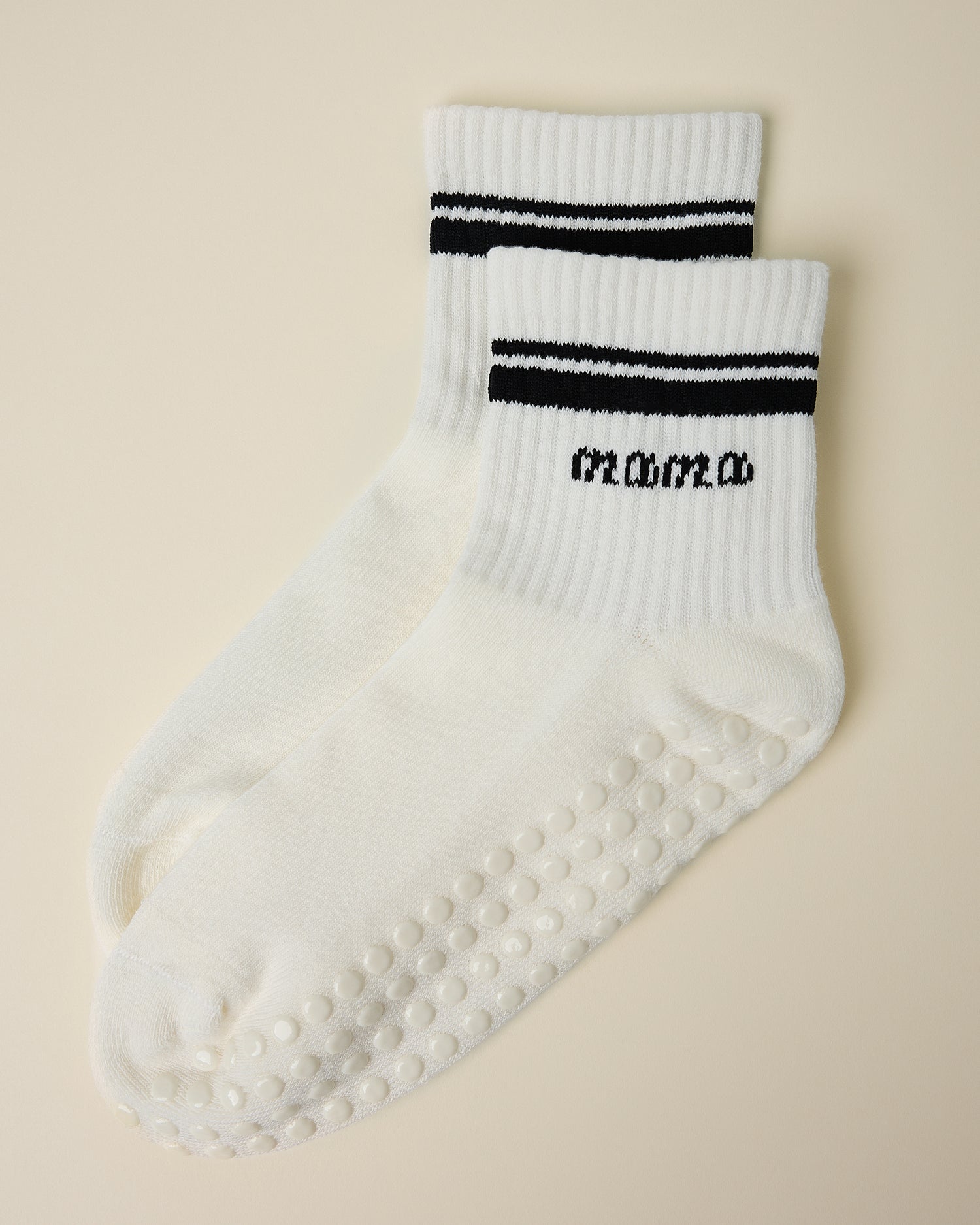 A pair of Non-Slip Quarter Crew Socks in Ivory & Black on a beige background.