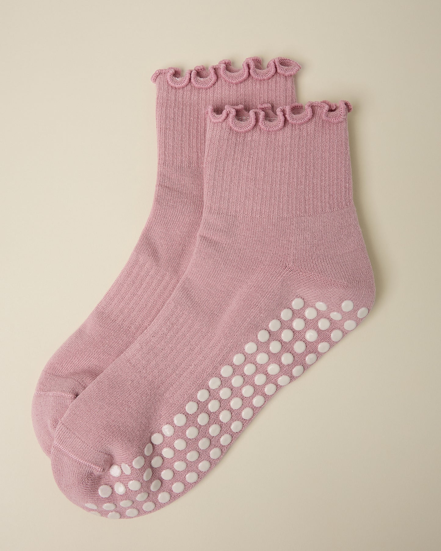 A pair of Non-Slip Ruffle Ankle Socks in Light Mauve on a beige background.