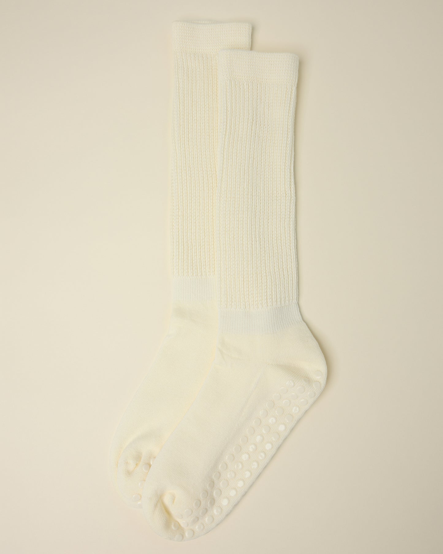A pair of Non-Slip Slouchy Socks in Cream on a beige background
