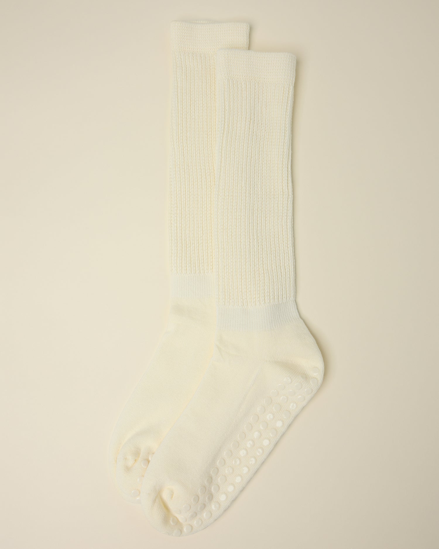 A pair of Non-Slip Slouchy Socks in Cream on a beige background