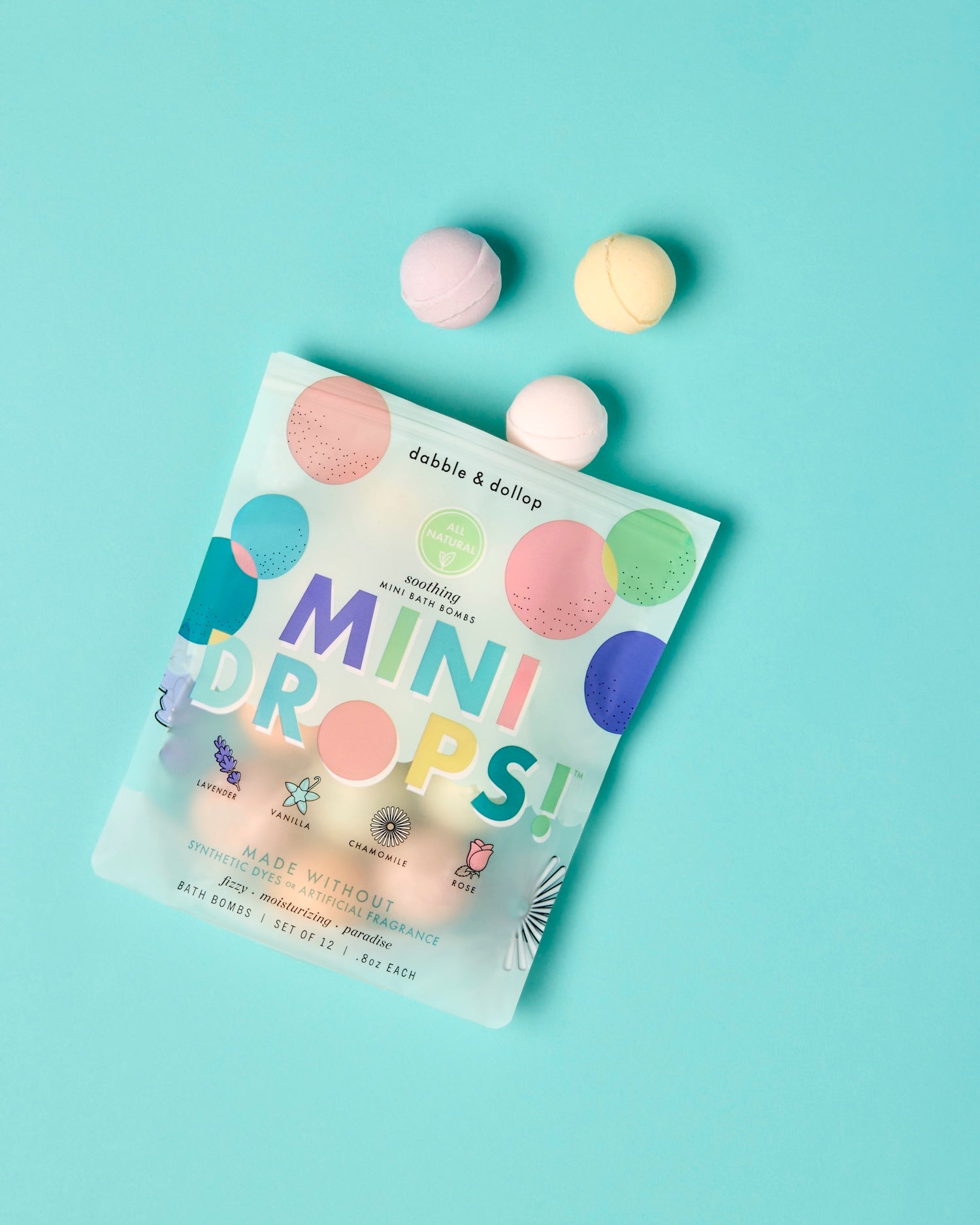 Package of dabble & dollop soothing mini bath bombs on a light blue background, showing a few bath bombs out of the package