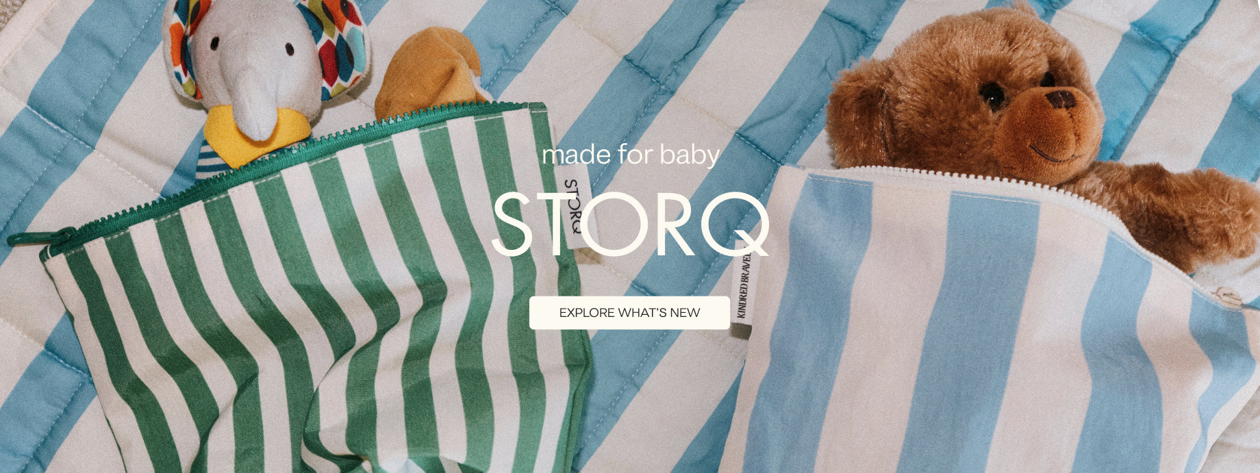 White text states: made for baby, STORQ. White button with text, Explore what's new. Image of Zipper Pouch Three-Piece Set in Stripe, laying on the Inside/Outside Play Mat in Blue Wide Stripe. Each bag is holding dolls, toys and loveys.
