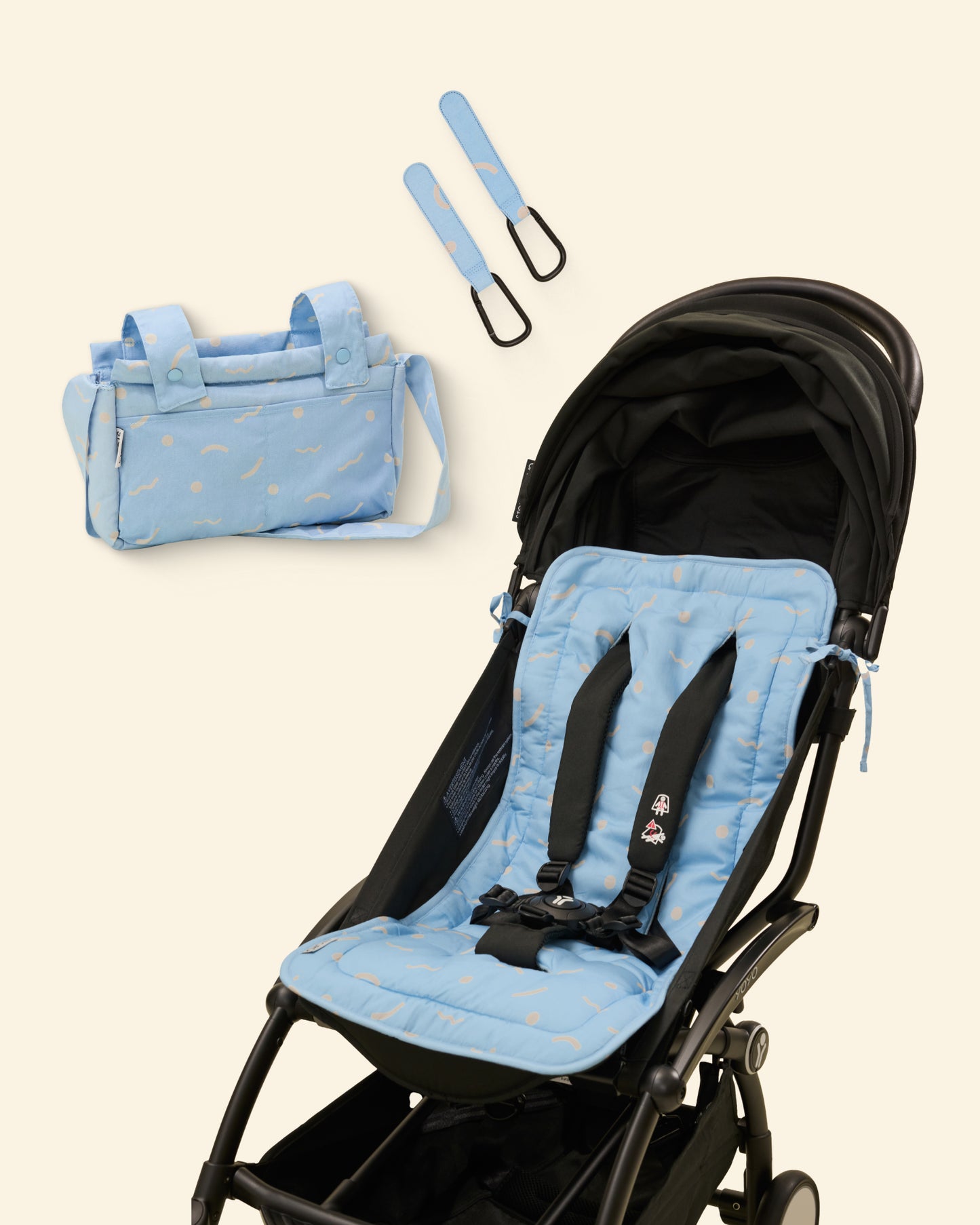 Blue and white wave patterned stroller seat cover with matching bag and stroller clip on a light background