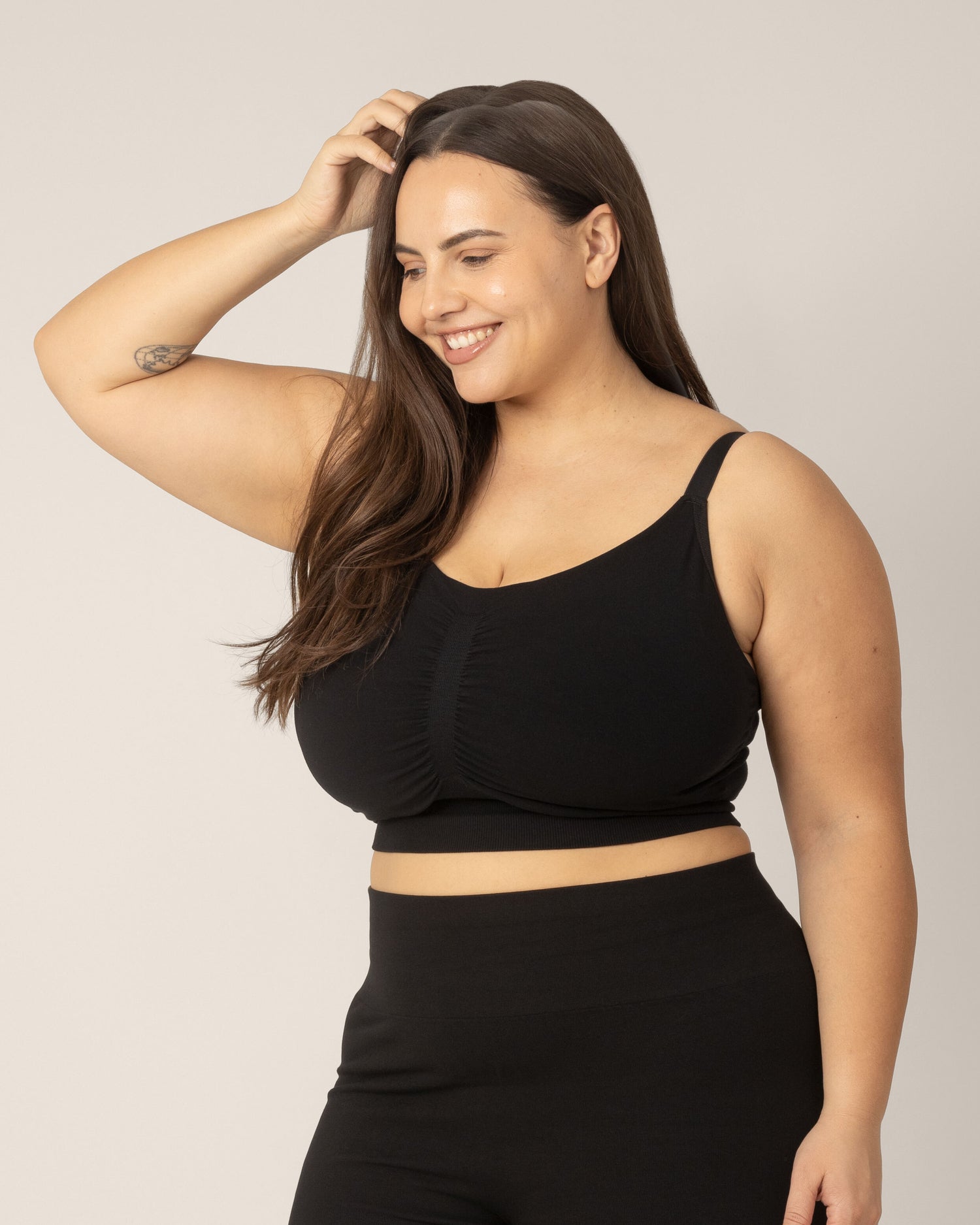 Side view of super busty model wearing the Sublime Hands-Free Pumping & Nursing Sleep and Lounge Bra in Black.@model_info:Anna is wearing a Large Super Busty.