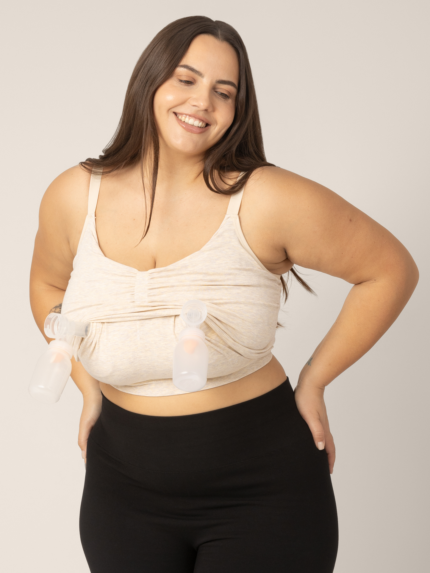 Super busty model wearing the Sublime Hands-Free Pumping & Nursing Sleep and Lounge Bra in Oatmeal Heather. She pulled up the pumping layer to insert pumps for hands-free pumping access.@model_info:Anna is wearing a Large Super Busty.