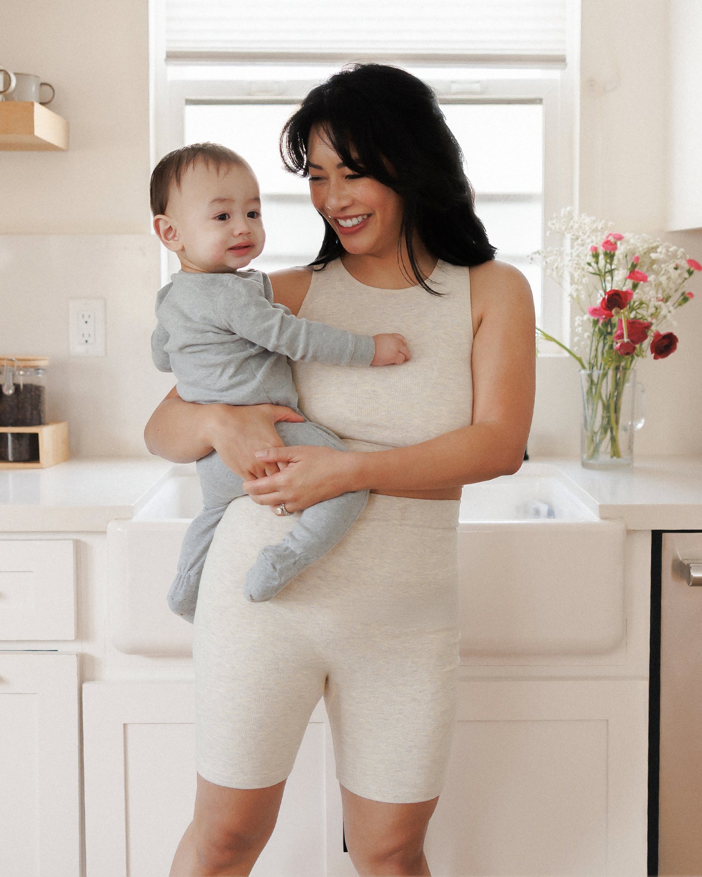 Model holding baby while wearing the Sublime® Bamboo Hands-Free Pumping Longline Bra Top in Oatmeal Heather @model_info:Nikki is wearing a Medium.