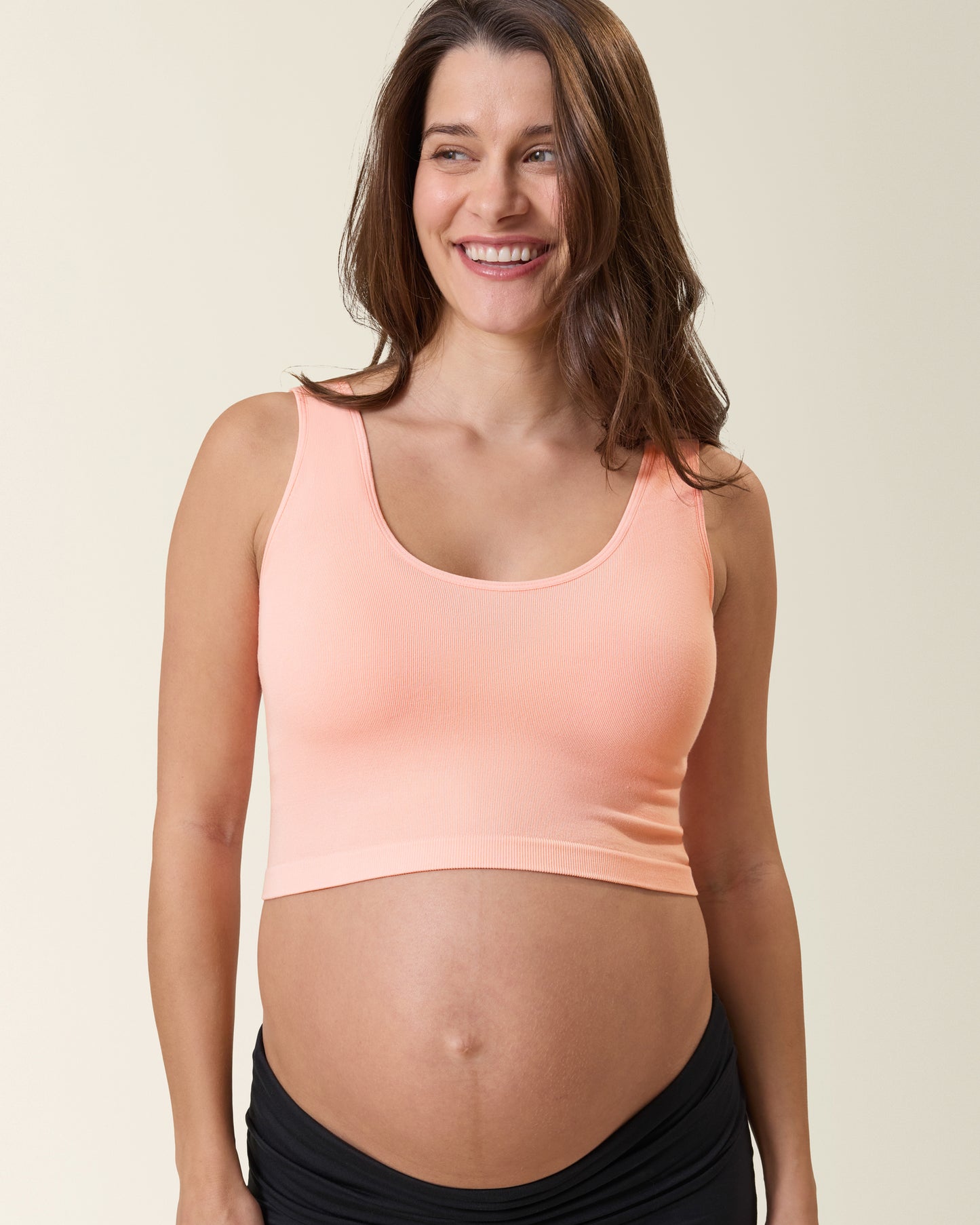 Model wearing Sublime® Bamboo Scoop Neck Maternity & Nursing Longline Bra Top in Sunset Pink against a neutral background@model_info:Elliana is wearing a Medium.