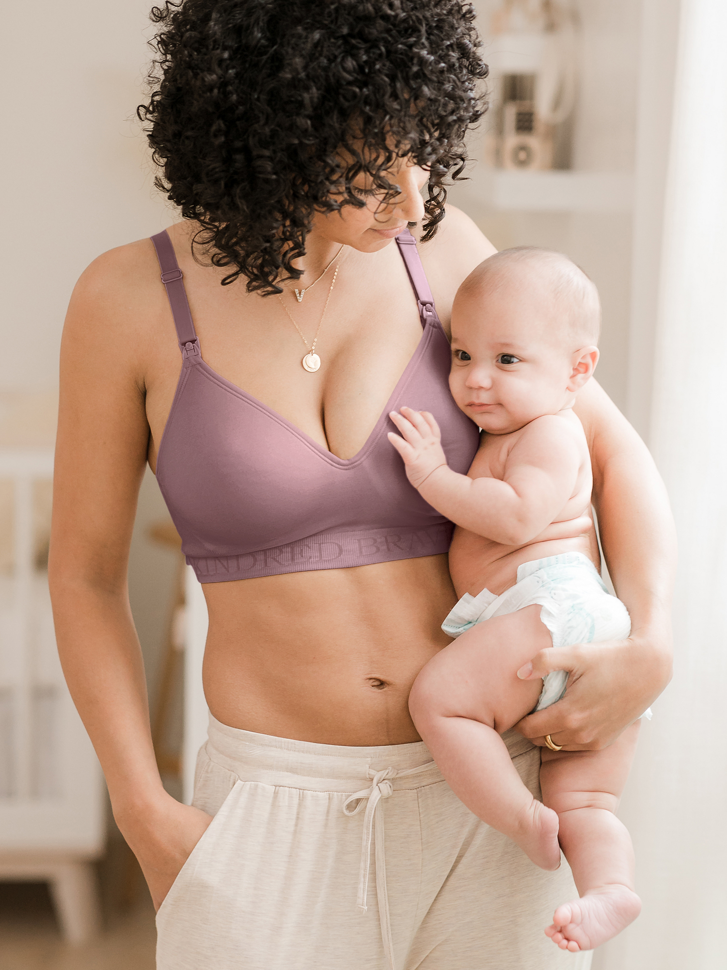 Model holding her baby on her hip while wearing the Signature Sublime® Contour Maternity & Nursing Bra in Twilight@model_info:Arion is wearing a Small.