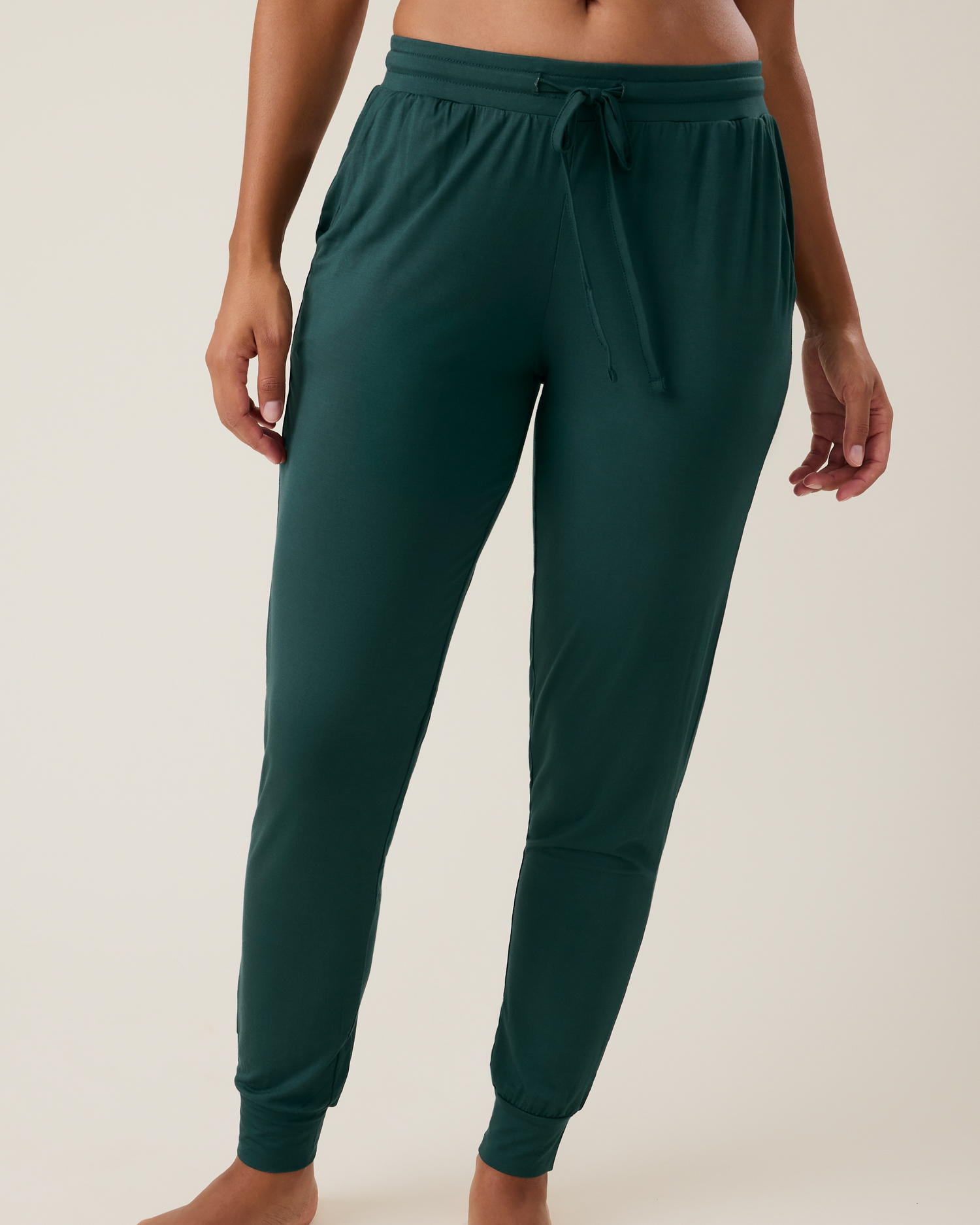 Green jogger pants worn by a person on a beige background