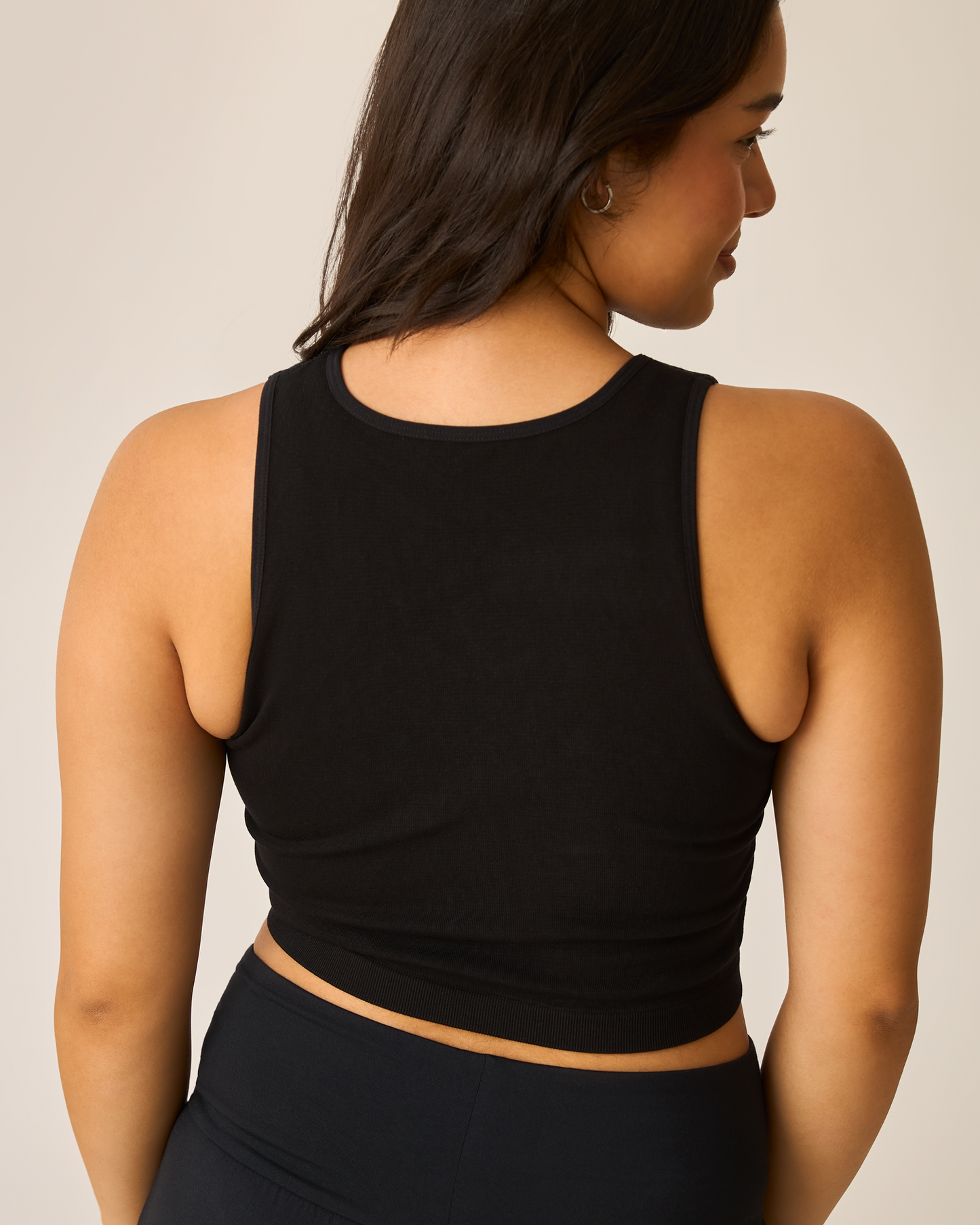 Woman wearing a black longline bra top against a neutral background