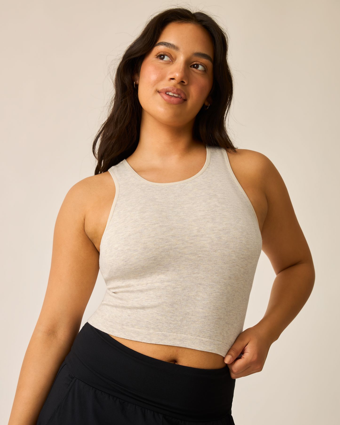 Woman wearing an oatmeal heather longline bra top against a plain background