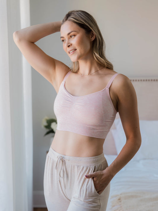 Model standing near a window wearing the Sublime® Bamboo Hands-Free Pumping Lounge & Sleep Bra in pink heather @model_info:Taylor is wearing a Medium Regular.