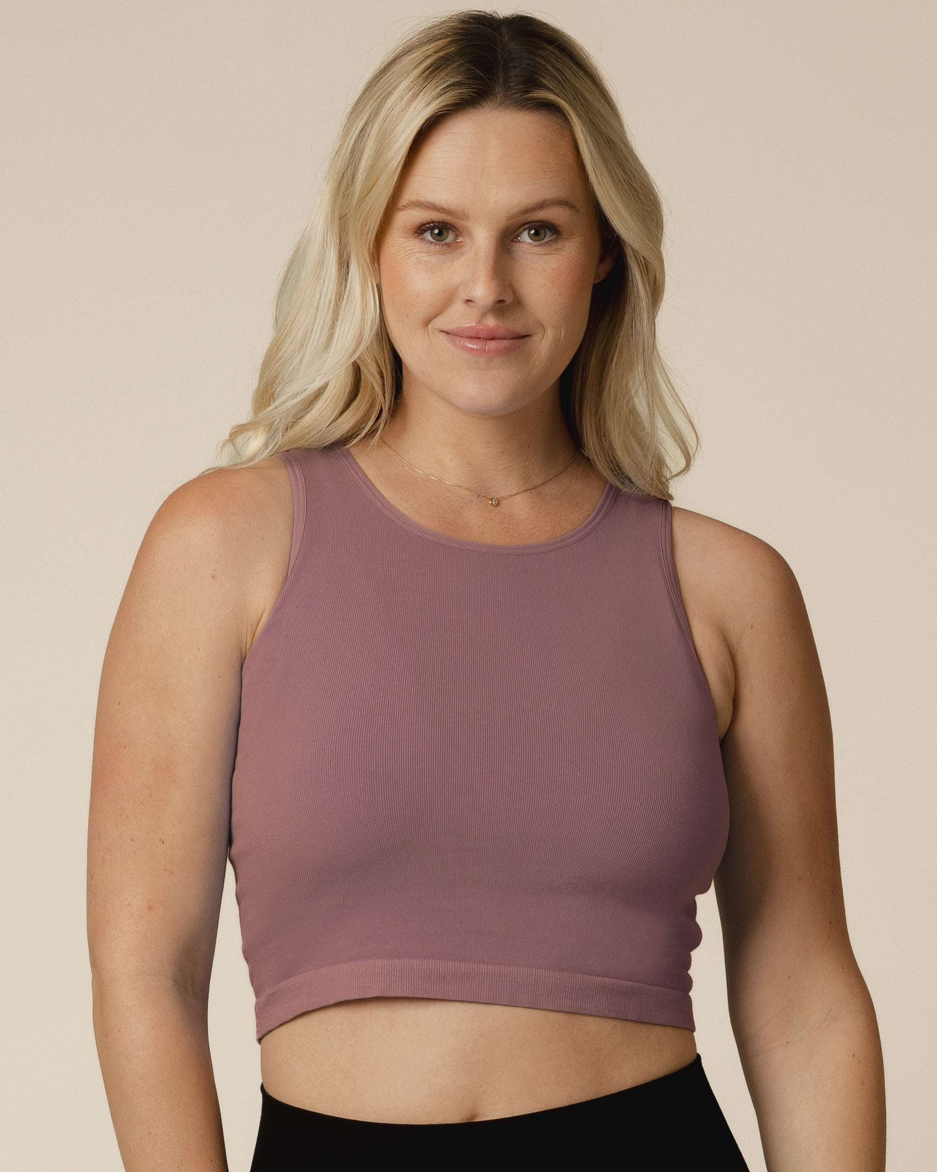 Woman wearing a purple longline bra top against a beige background