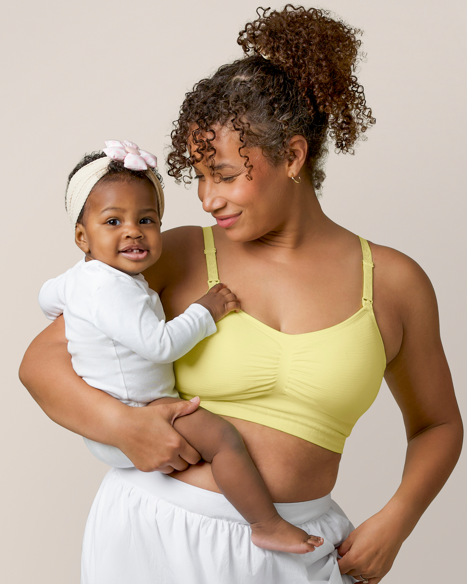 Front view of model holding baby and wearing the Sublime® Hands-Free Pumping & Nursing Bra Light Lemon