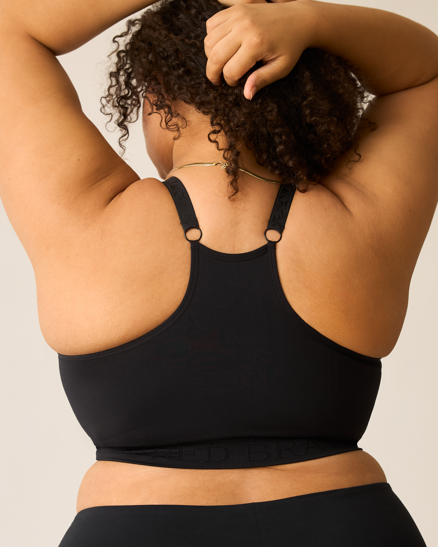 Person wearing a black sports bra with a neutral background