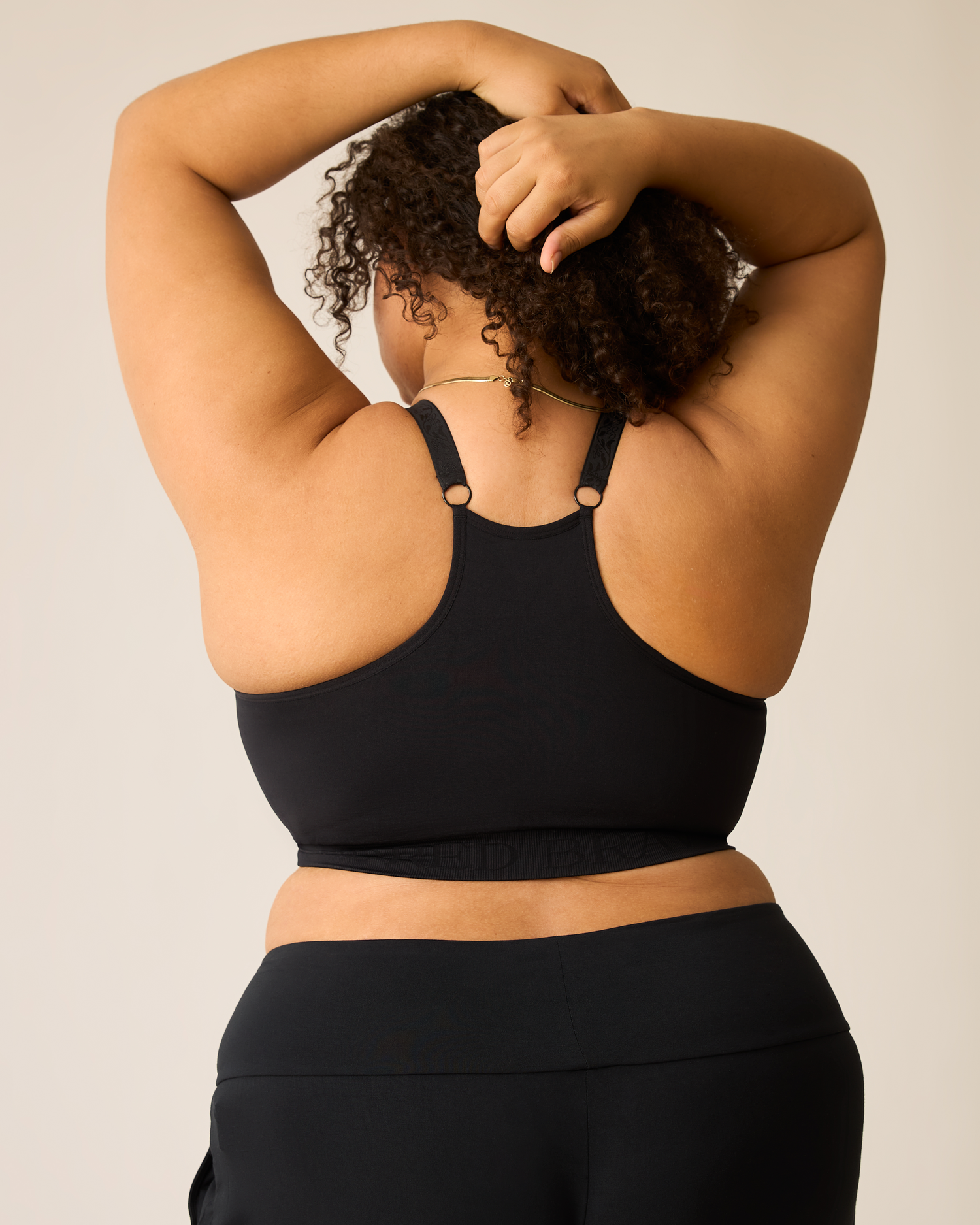 Woman wearing the Sublime® Nursing Sports Bra in black, showing racerback against a neutral background
