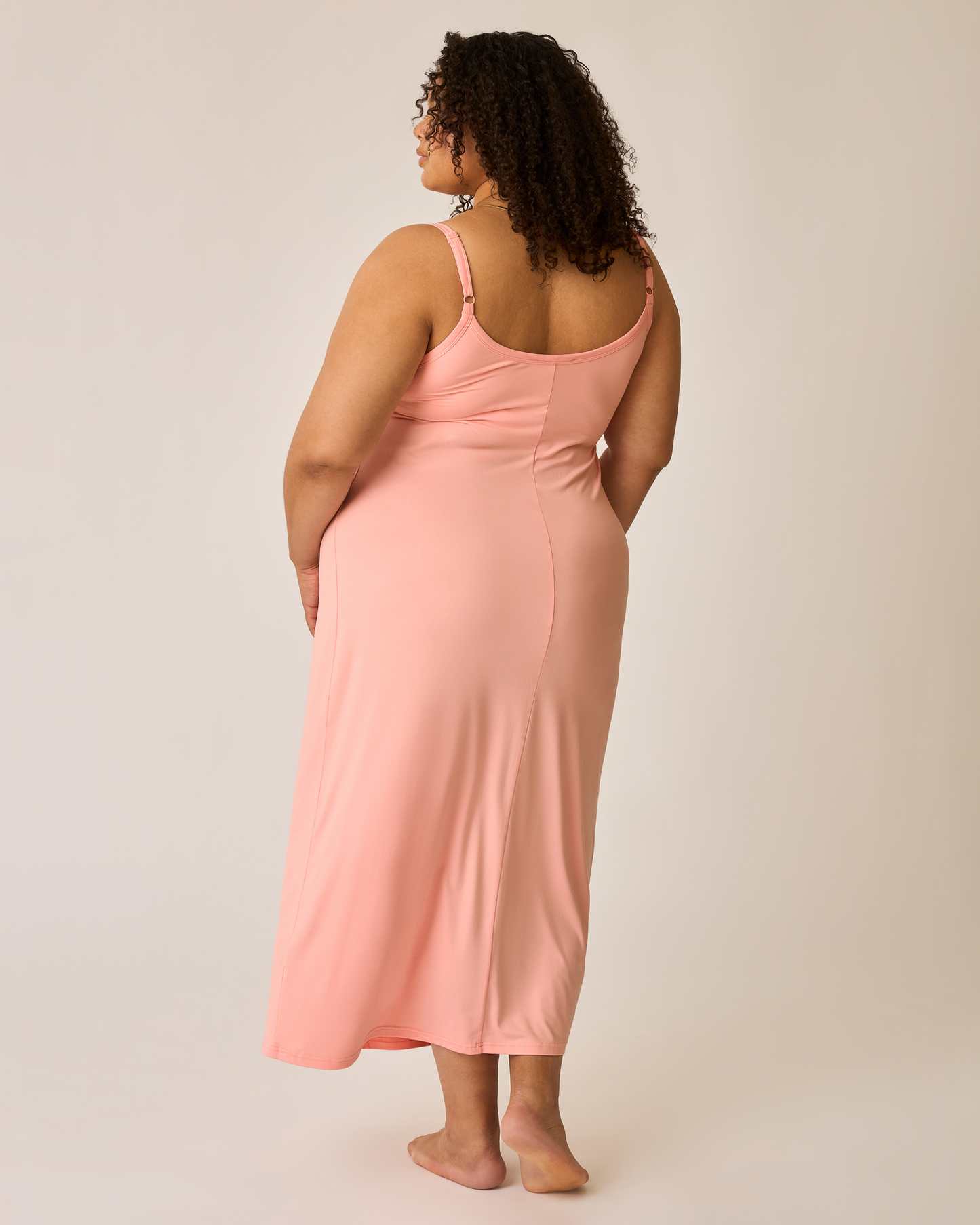 Woman wearing a pink nightgown against a plain background