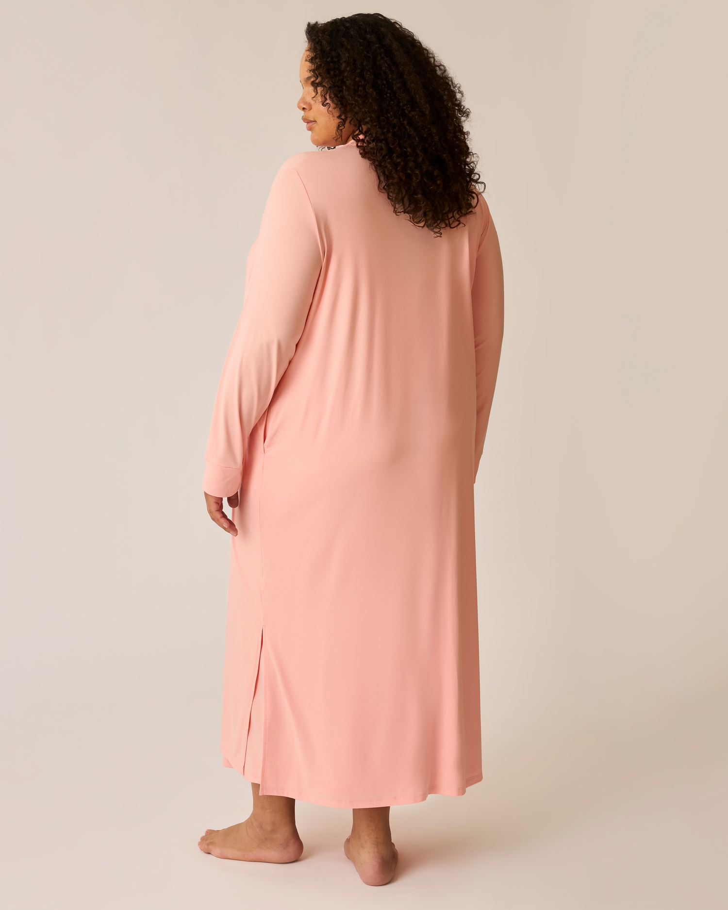 Woman wearing a long pink duster against a beige background