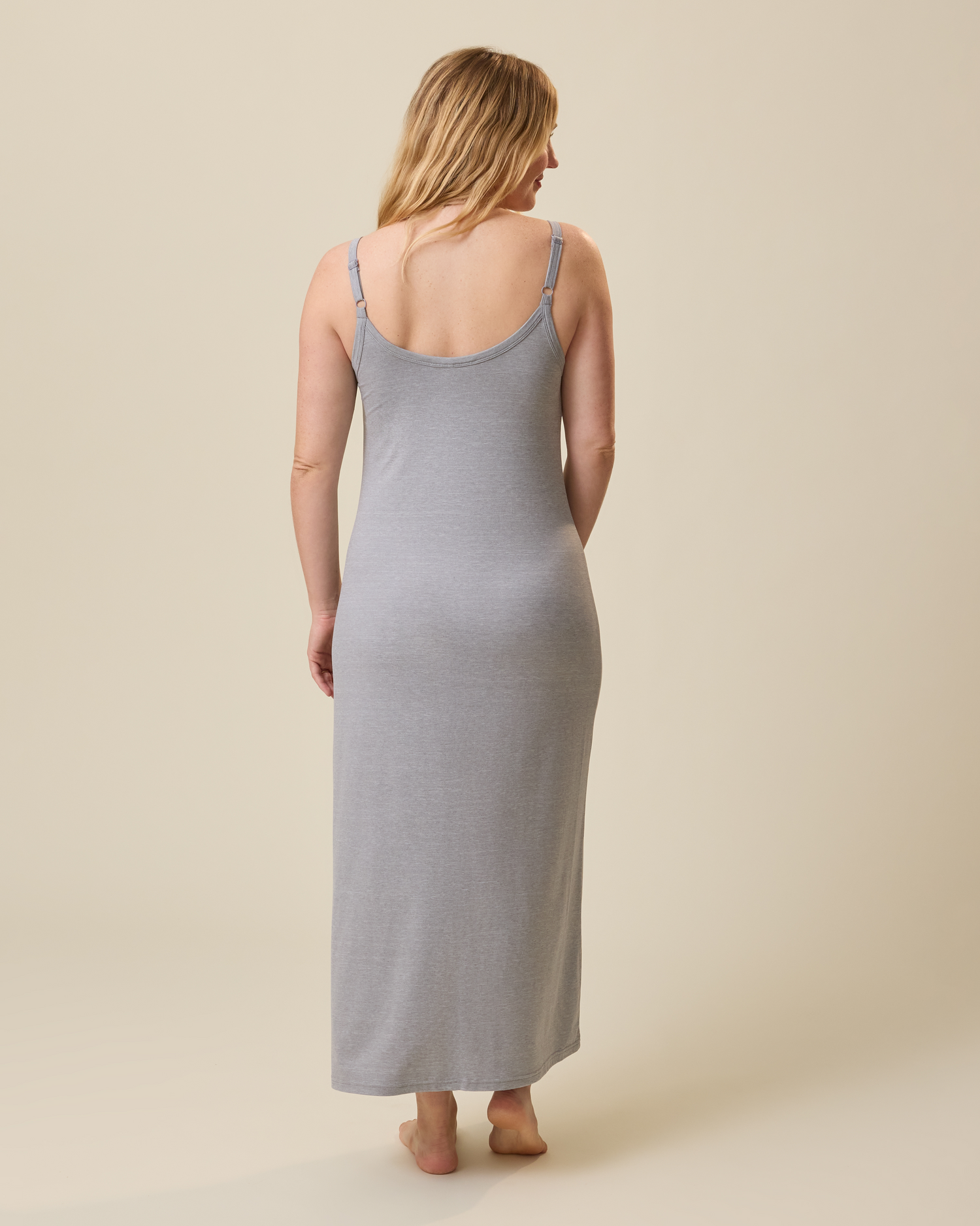Woman wearing a gray lounge dress against a beige background