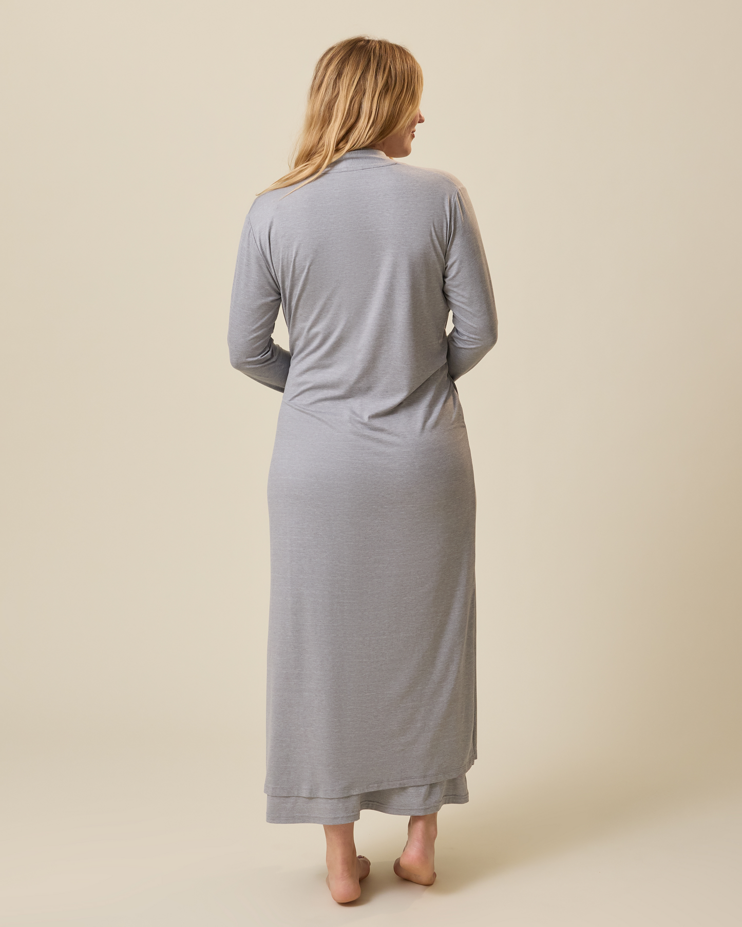 Woman wearing a long gray duster against a beige background