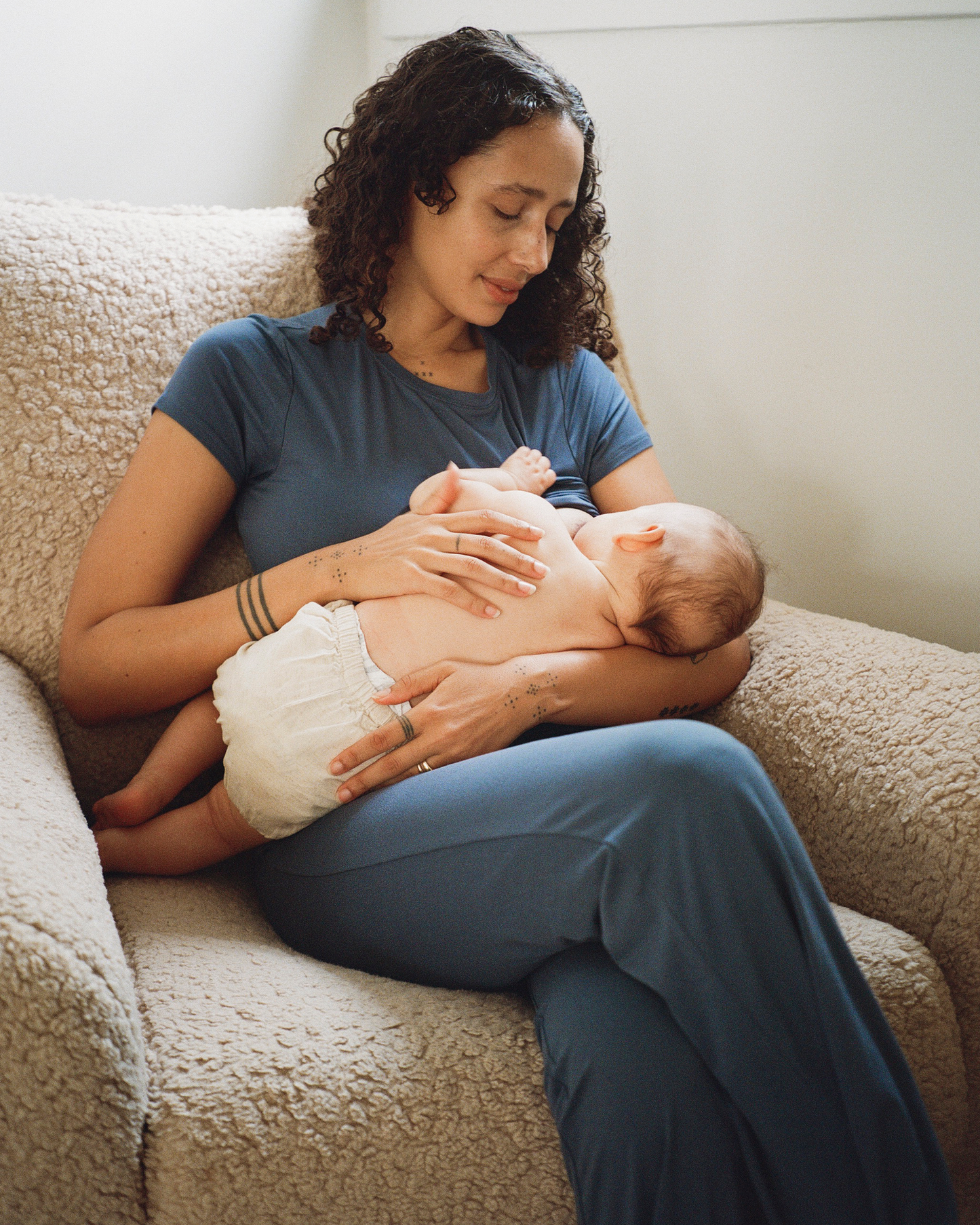 Woman breastfeeding a baby on a couch wearing the Sunday Set Lounge Set in Slate Blue@model_info:Natasha is 5'9" and wearing a Small.