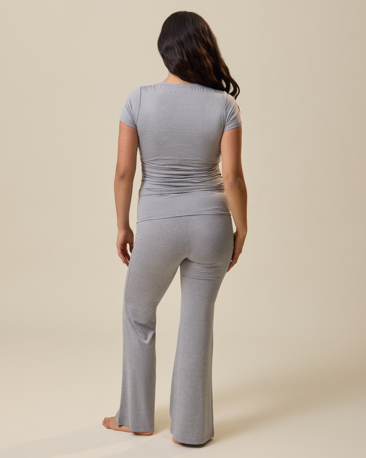 Woman wearing a gray heather outfit standing against a beige background