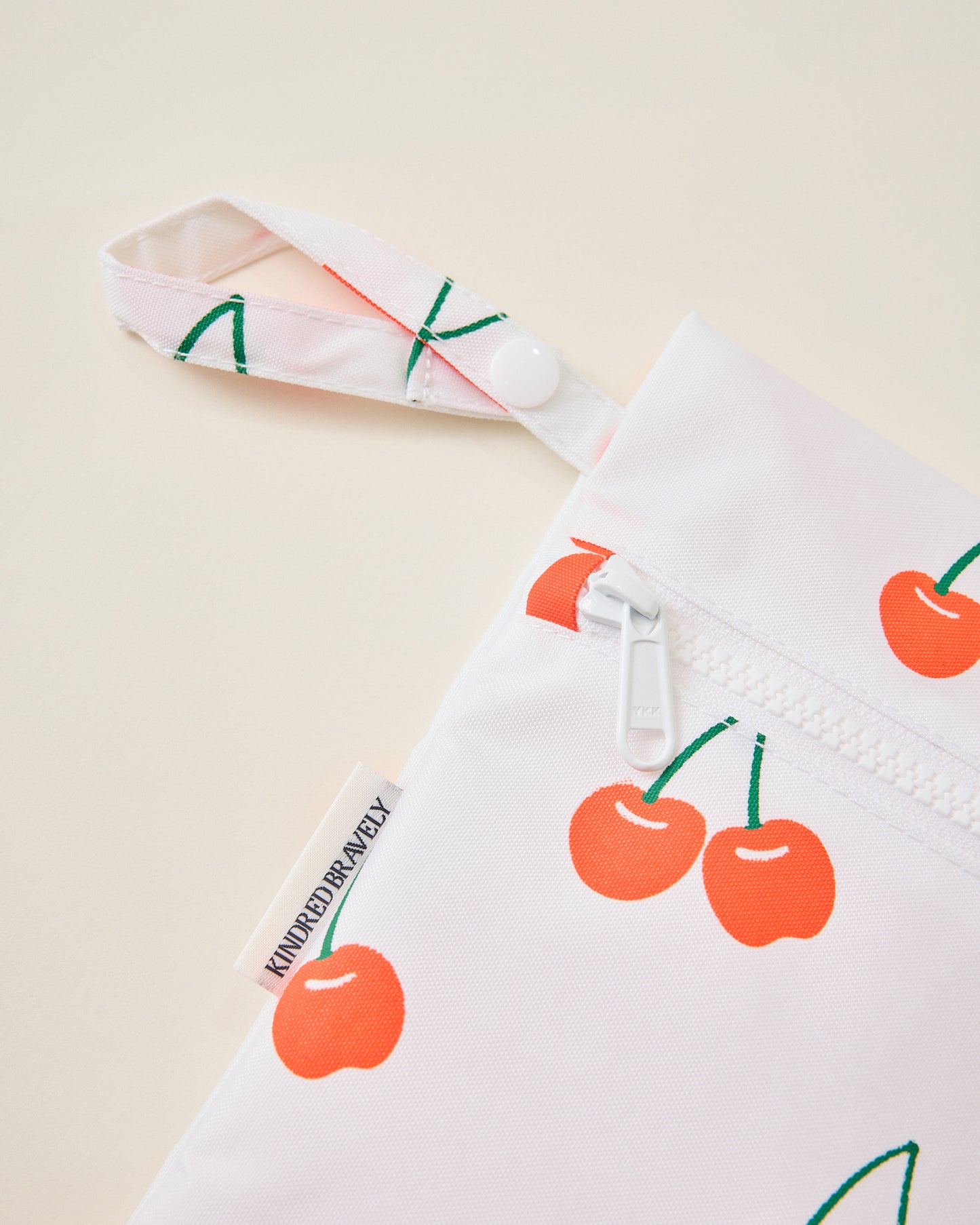 Close up of Wet/Dry Bag Set in Cherries print on beige background