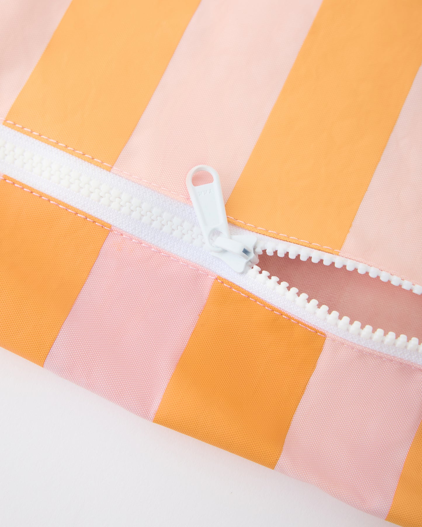 Close up of zipper on Wet/Dry Bag Set in Pink Stripe on a beige background