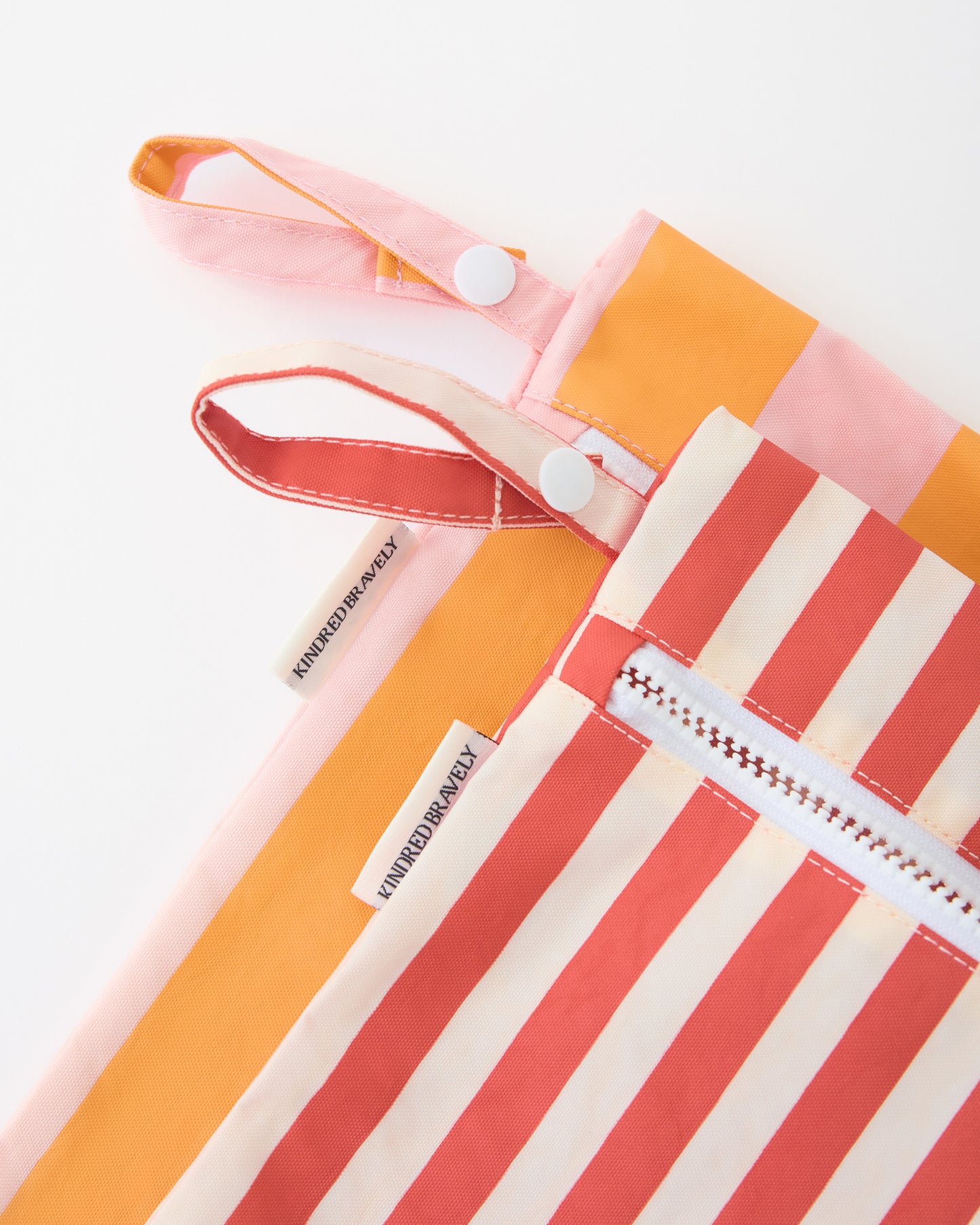 Close up of zipper and strap on Wet/Dry Bag Set in Pink Stripe on a beige background