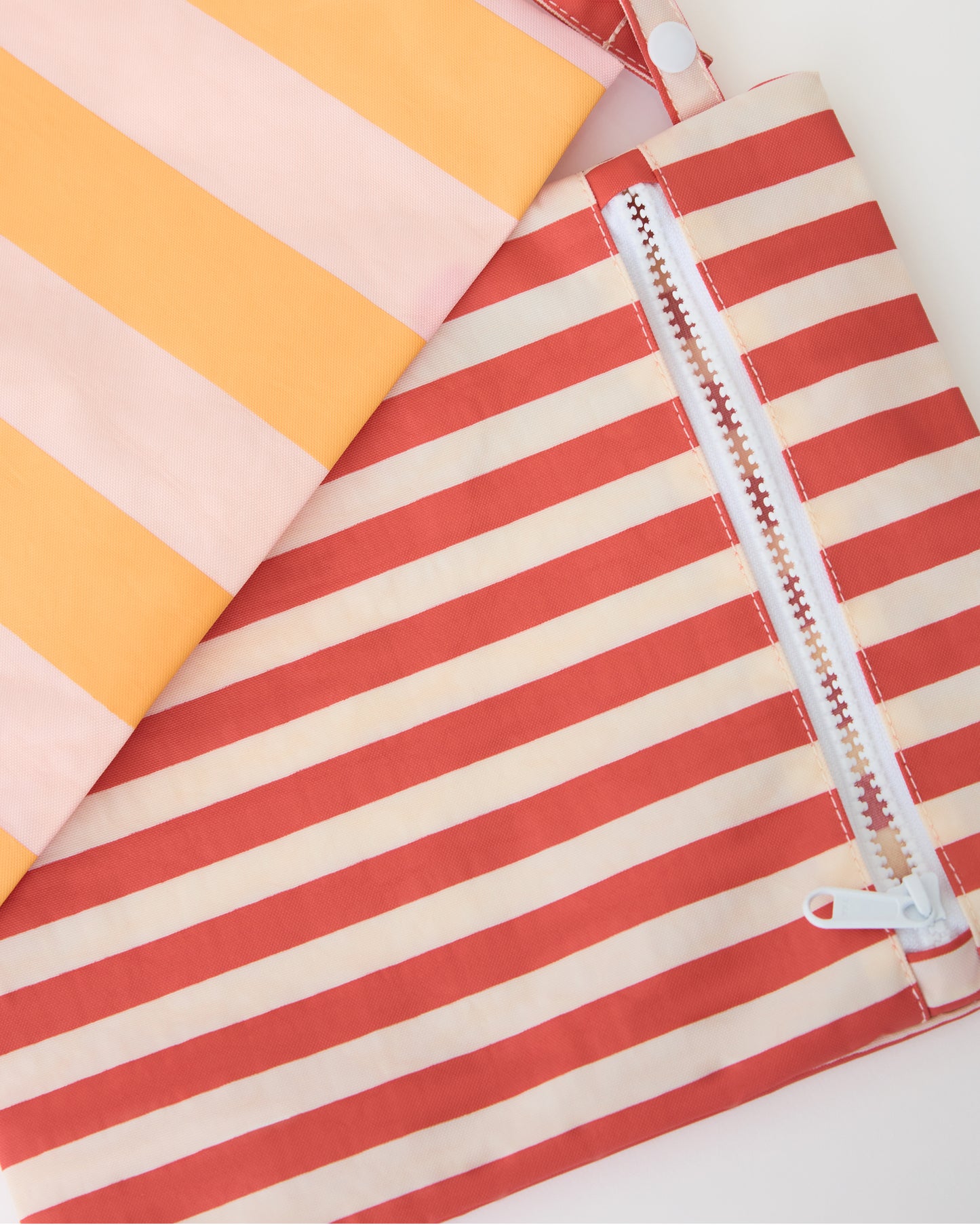 Close up of zipper on Wet/Dry Bag Set in Pink Stripe on a beige background