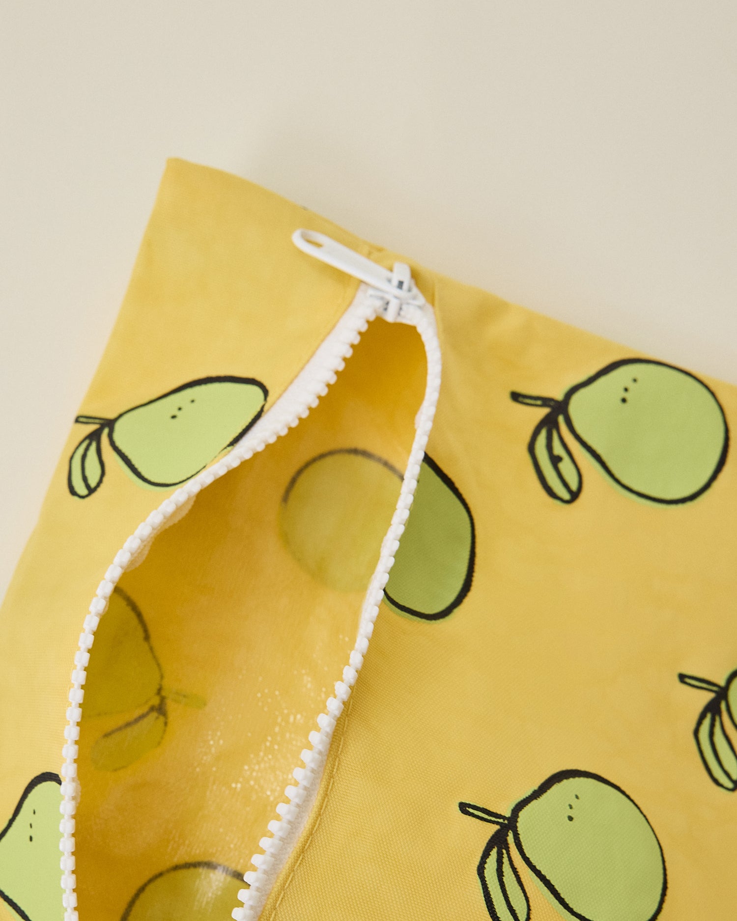 Close up of Wet/Dry Bag Set in Pomelo print unzipped, on beige background