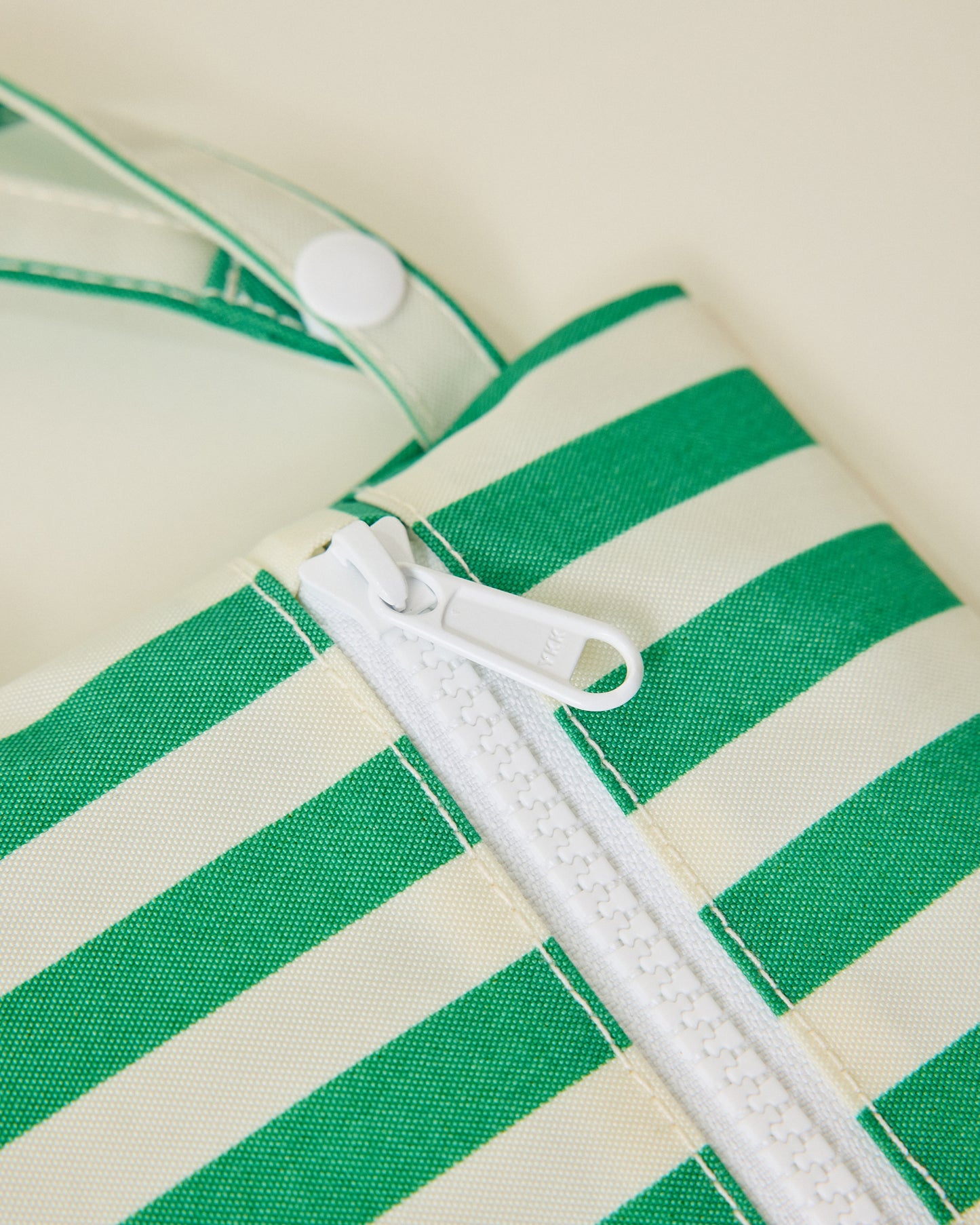 Close up of wide green stripe bag of Wet/Dry Bag Set in Stripe print, on beige background