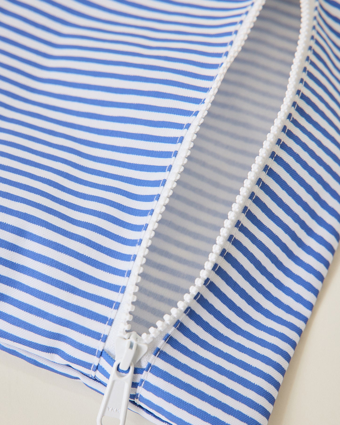 Close up of Wet/Dry Bag Set in Stripe print unzipped, on beige background